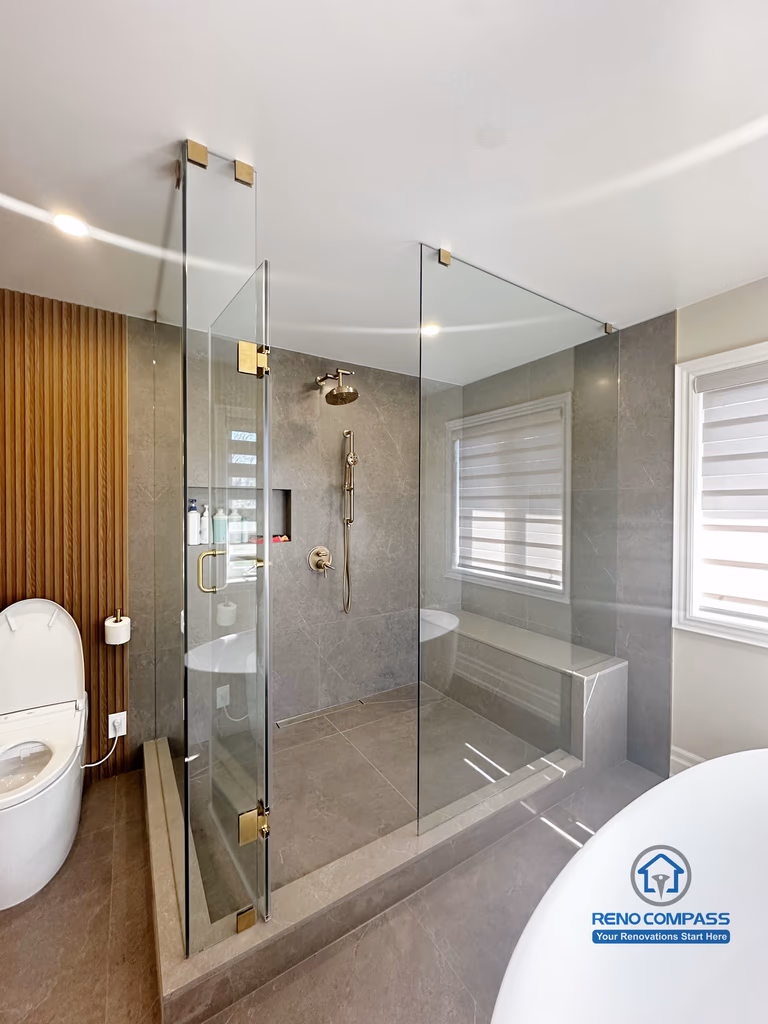 This bathroom renovation in North York combines a frameless glass shower enclosure with a freestanding tub and soft natural light. The spacious layout and refined material selection create a luxury spa-like experience.