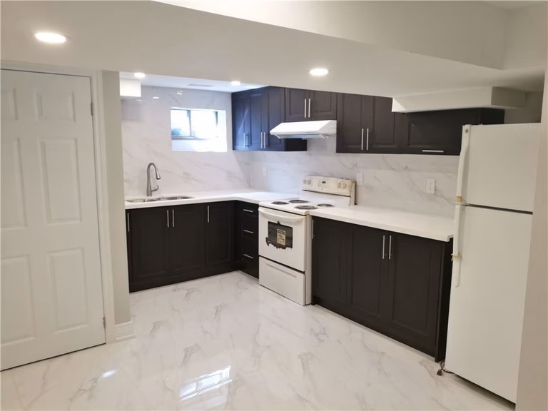 Scarborough whole-house interior renovation featuring a newly finished basement kitchen with modern dark cabinetry, quartz-style countertops, and upgraded tile flooring. This renovation highlights improved functionality, bright lighting, and a clean contemporary layout completed by a professional Toronto renovation contractor.