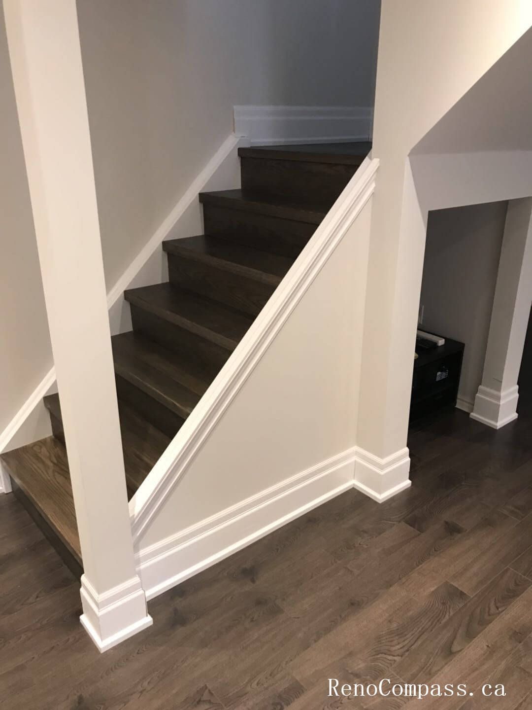 This image shows a newly finished staircase landing in a renovated Richmond Hill basement, featuring upgraded hardwood steps, clean white trim, and modern wall finishes. The refined detailing creates a smooth, stylish transition between the basement and upper level. Renovation completed by Reno Compass Inc.