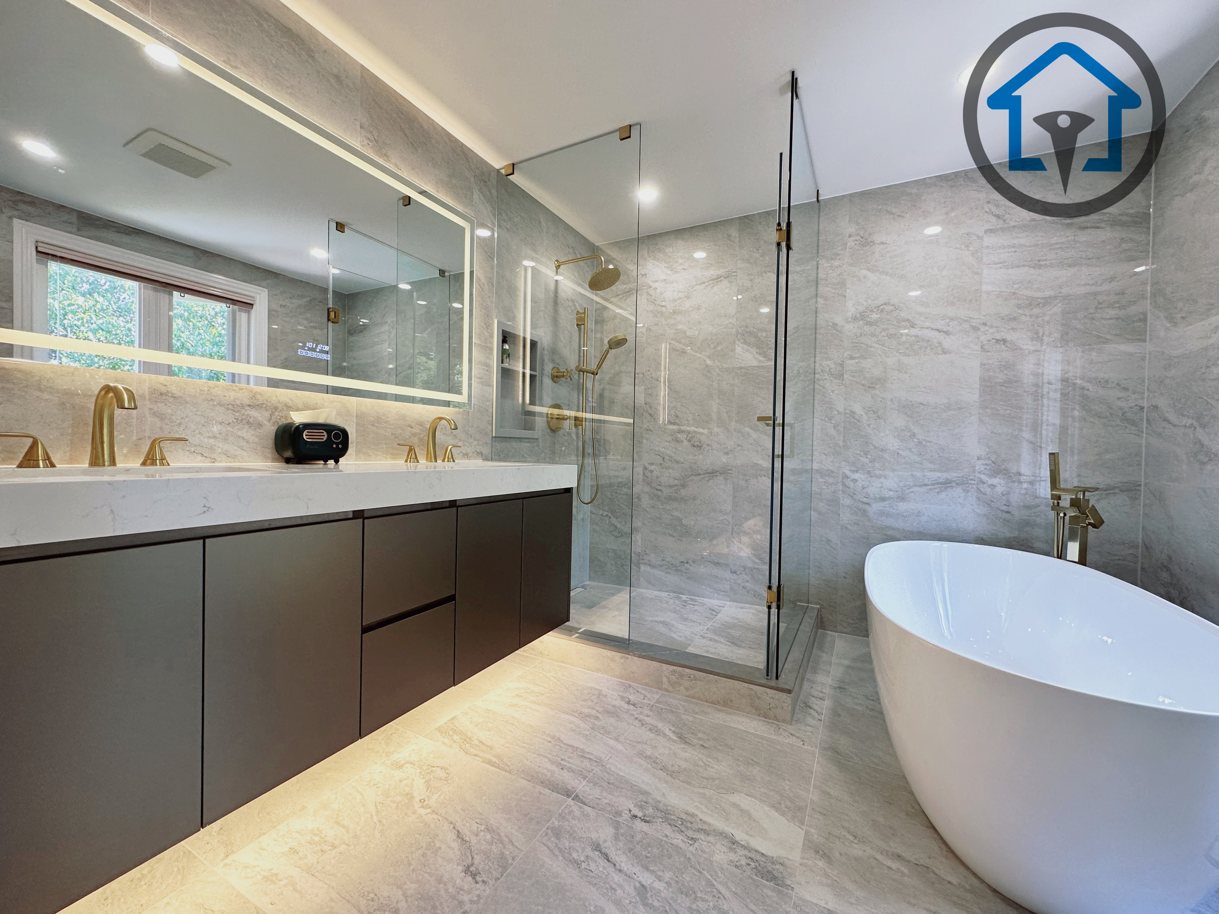 Modern bathroom completed as part of a North York interior renovation, featuring a custom double vanity, integrated LED mirror, large-format marble-look tile, and a frameless glass shower with brushed gold fixtures. The layout emphasizes clean lines, moisture-resistant materials, and a balanced mix of luxury and everyday functionality, completed by a professional Toronto renovation company.