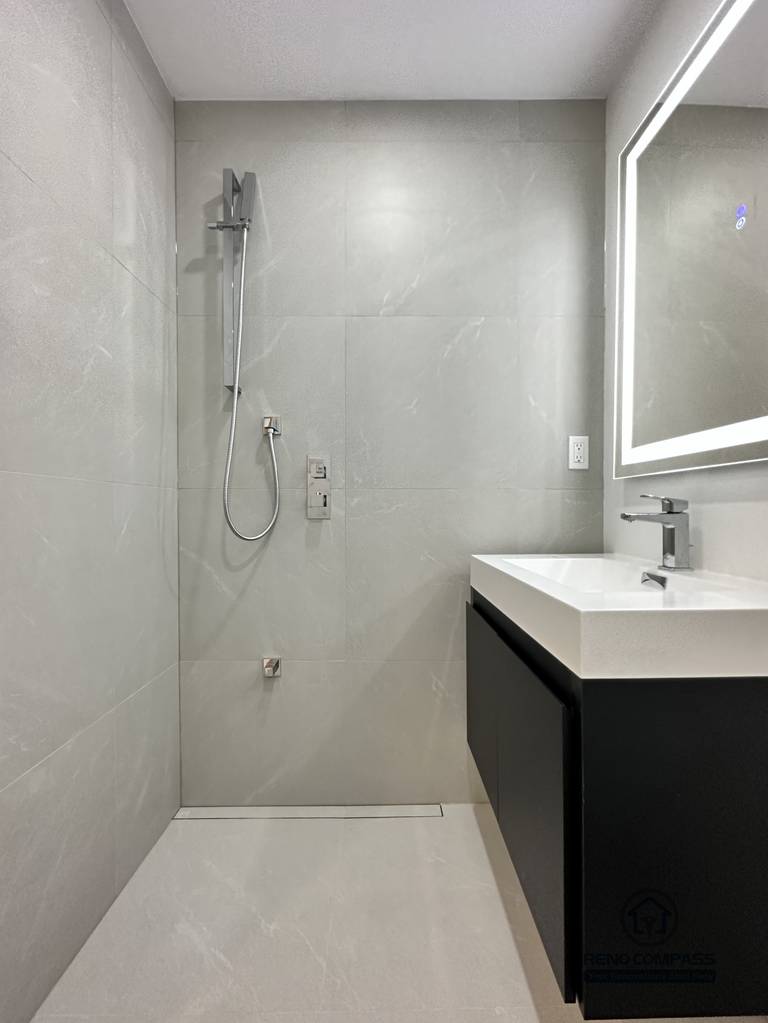This image highlights a barrier-free walk-in shower designed for a pet-friendly accessible bathroom renovation in Brampton. The curbless shower entry, linear floor drain, and large-format wall tiles create a seamless, easy-to-clean space that is safe for both pets and homeowners. A handheld shower system allows flexible use for pet bathing, while the open layout improves accessibility and mobility. This modern, functional design reflects the expertise of a professional Toronto Renovation Company specializing in accessible and pet-conscious bathroom renovations.
