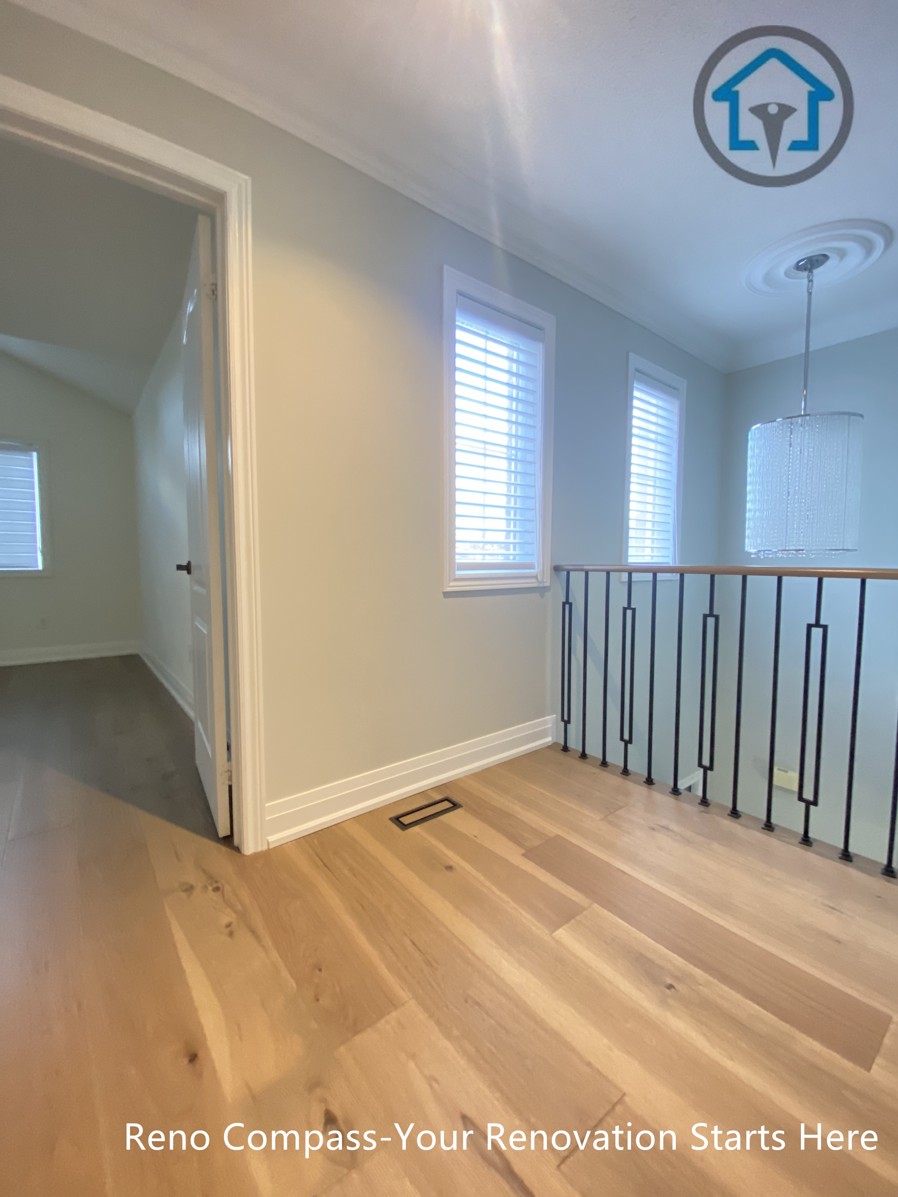 This image shows the upper hallway and stair landing area of a flooring and staircase renovation project in Richmond Hill. The space features continuous hardwood flooring, clean wall finishes, and modern black iron railings that create a safe yet visually open transition between rooms and levels. Natural light from multiple windows enhances the brightness and depth of the hallway. Completed by a reliable Toronto renovation company, the renovation emphasizes smooth circulation, durable materials, and a cohesive modern interior design.