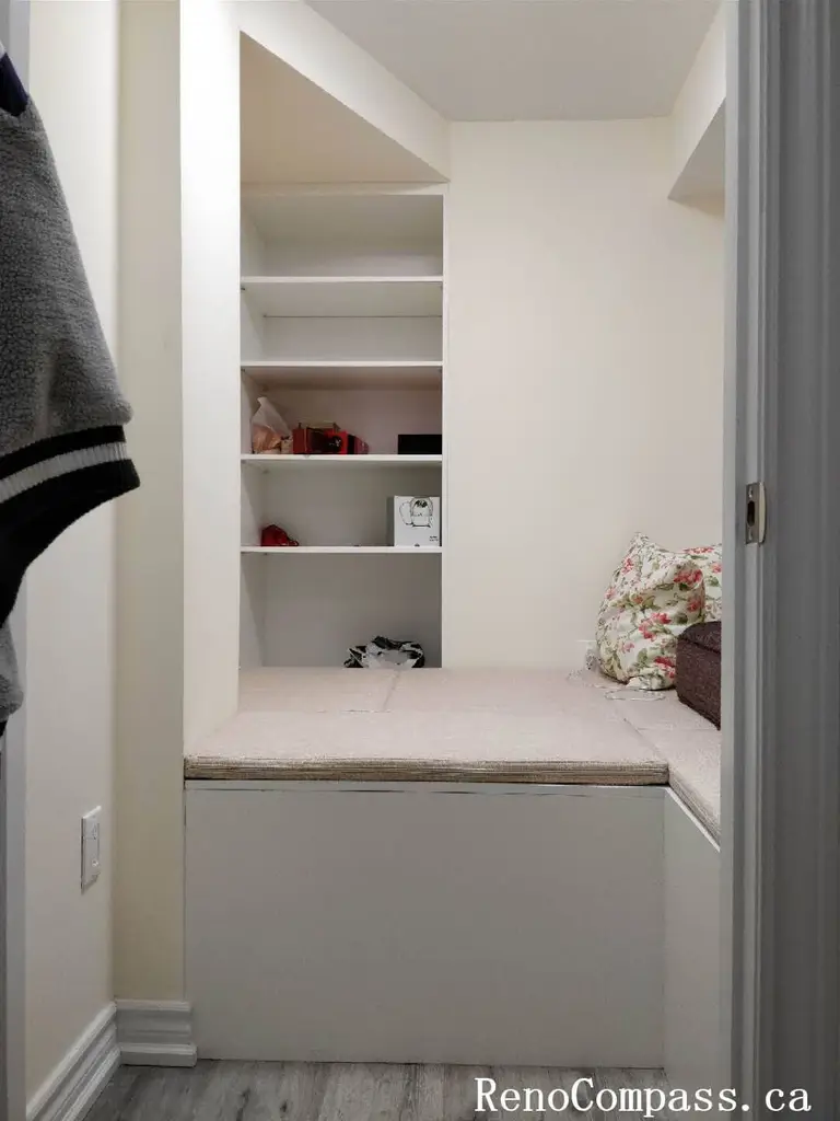 A high-quality custom mudroom renovation in Markham featuring white shaker-style lower cabinets, a built-in seating bench, open cubby shelving, and an integrated garment hanging rod for maximum organization.