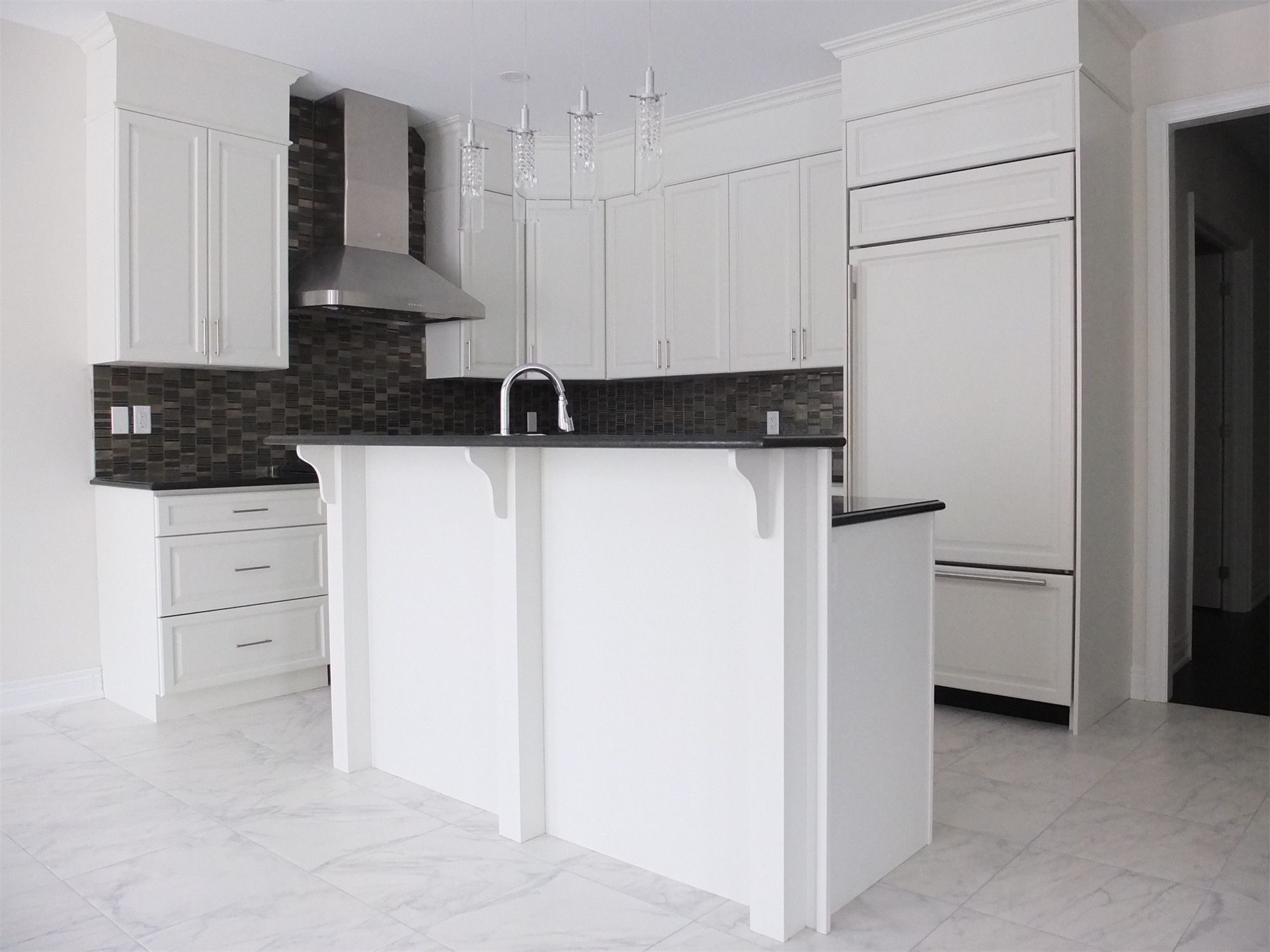 This Kleinburg interior renovation features a bright and elegant modern kitchen with custom white cabinetry, marble-style flooring, and a functional island with built-in sink. The design combines clean lines, stainless steel appliances, and a dark mosaic backsplash to create a refined contrast while maintaining a spacious and contemporary feel. The kitchen island also provides additional workspace and seating, making the space both stylish and highly practical for everyday living.