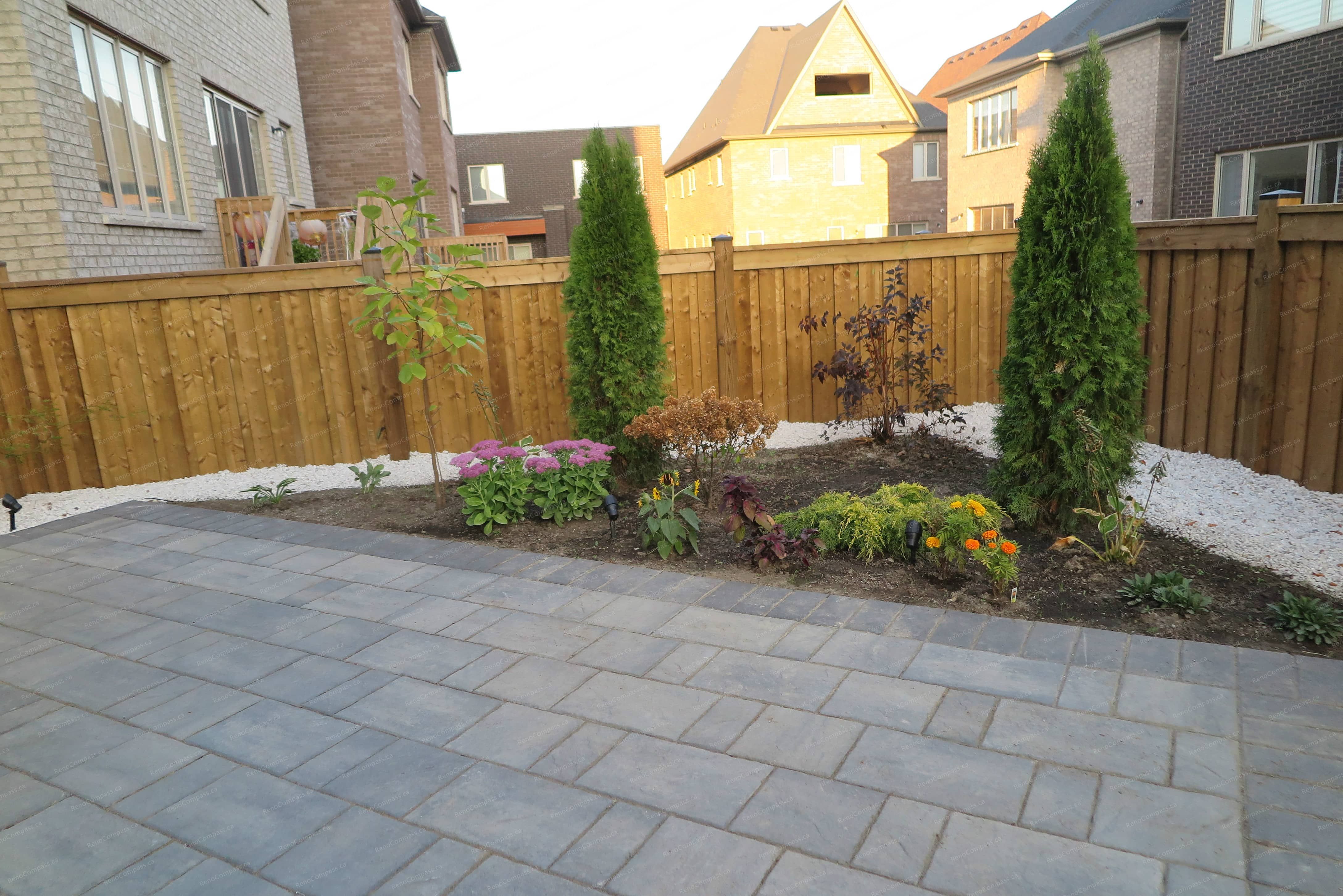 This Vaughan backyard landscaping project features a professionally installed interlock patio with decorative stone accents and thoughtfully designed garden beds. The layout combines durable paving, river rock details, and seasonal plants to create a modern and low-maintenance outdoor living space. Completed with precision and landscaping expertise by Reno Compass Inc.
