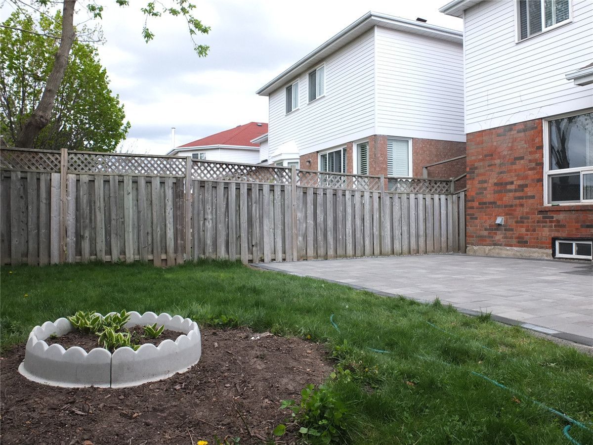 A completed backyard landscaping project in Mississauga featuring a newly installed interlocking stone patio, green lawn area, and decorative garden bed. The grey patio pavers create a clean and durable outdoor space while the surrounding landscaping adds natural balance to the backyard design. Completed by a professional Toronto Renovation Company, Reno Compass Inc., specializing in interlocking patios, landscaping, and exterior home upgrades across the GTA.