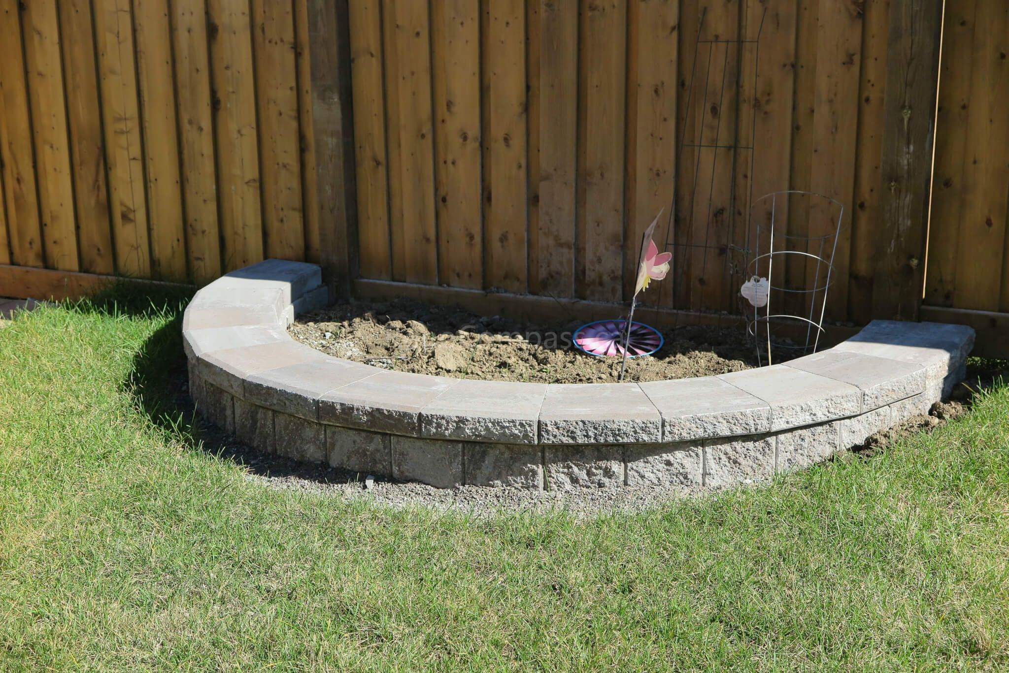 Custom curved garden bed and retaining wall completed in this Aurora backyard landscaping project. The stone border design creates a clean planting area against the wooden fence while maintaining a modern and low-maintenance outdoor layout. Professionally installed by Reno Compass Inc., a trusted Toronto landscaping and renovation contractor serving Aurora and the GTA.