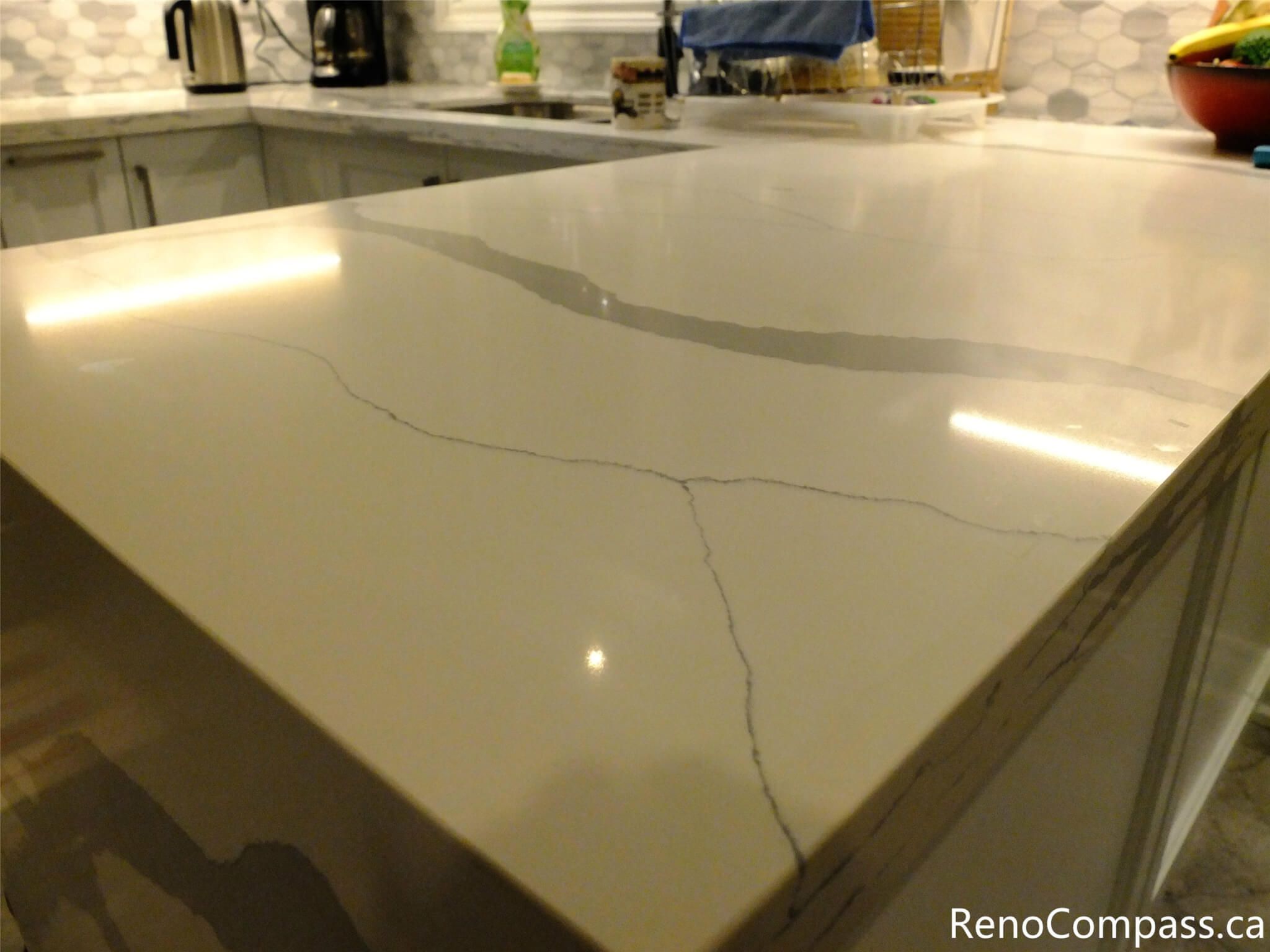This close-up image showcases the quartz waterfall island detail in a North York kitchen renovation, highlighting the natural veining, polished edge finish, and seamless countertop installation. The durable quartz surface adds both elegance and functionality, completed as part of a high-quality kitchen project by a trusted Toronto renovation company.