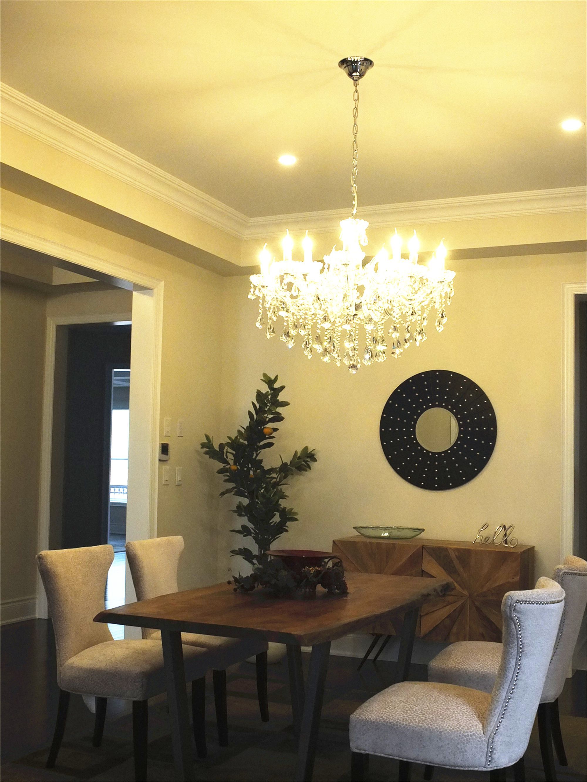 This Kleinburg interior renovation showcases an elegant dining room featuring a crystal chandelier, modern wooden dining table, upholstered chairs, and decorative wall accents. The warm lighting and refined design create a welcoming dining atmosphere, completed by a professional Toronto renovation company focused on both style and functionality.