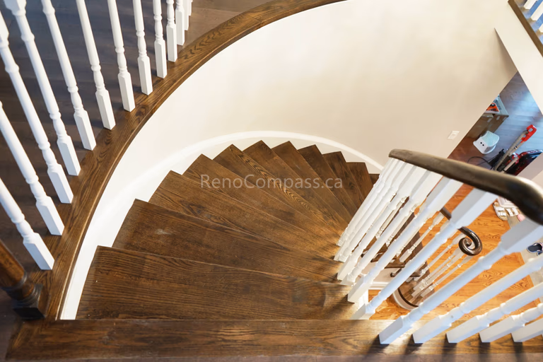 This North York interior renovation showcases a beautifully upgraded curved staircase featuring refinished hardwood steps, white spindles, and a smooth modern handrail. The elegant stair design enhances the entryway and adds architectural character while matching the warm hardwood flooring throughout the home. Completed by Reno Compass Inc., delivering professional interior renovation and staircase upgrade services across North York and the Greater Toronto Area.