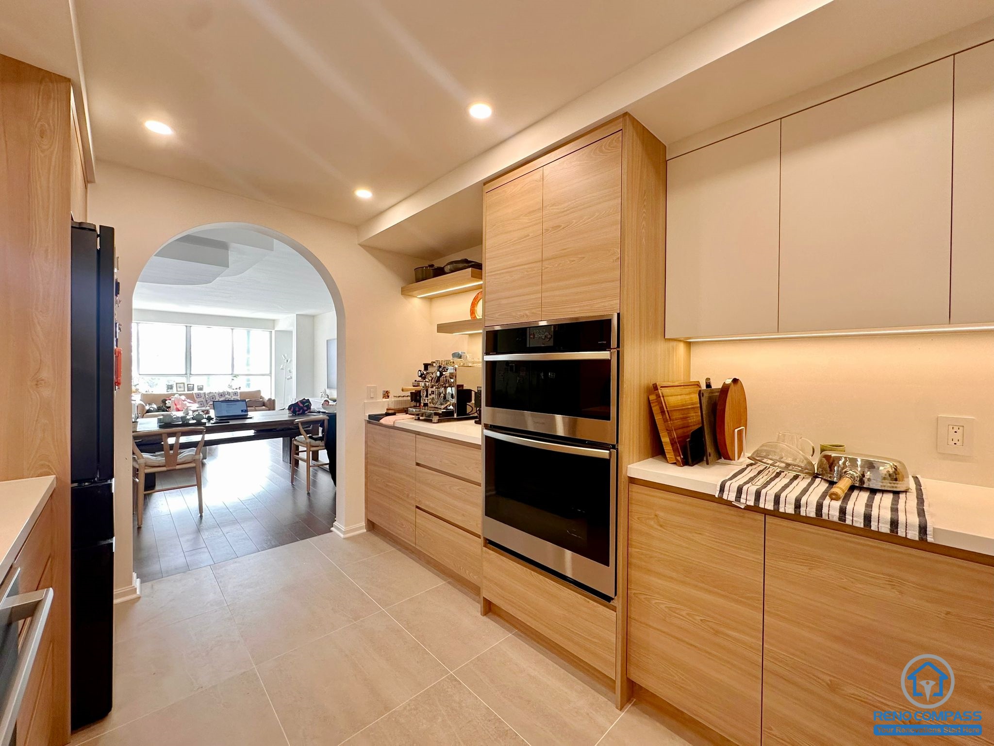 This Toronto condo kitchen renovation features a beautiful custom wood cabinetry design with a modern arch detail that enhances the overall elegance of the space. The open layout makes the kitchen feel spacious and bright, while the clean lines and warm finishes create a welcoming contemporary atmosphere.
