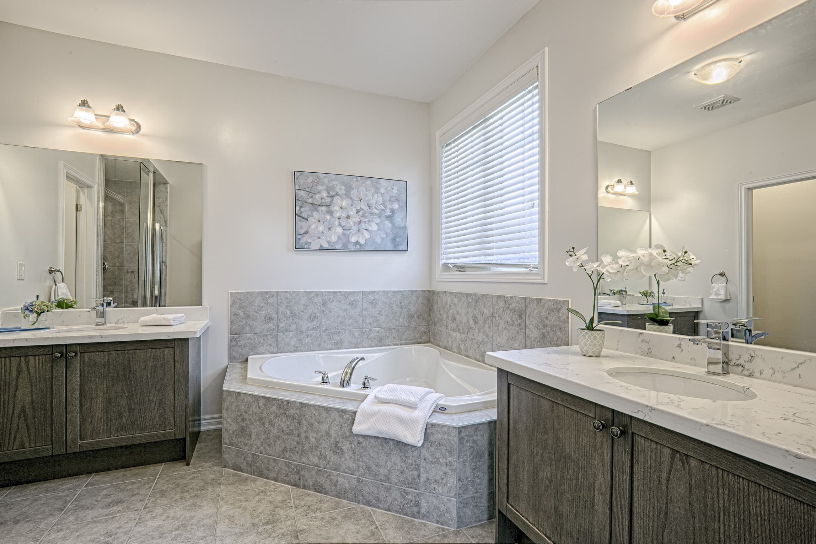 This Toronto luxury master bathroom renovation features a spacious layout with a double vanity, premium stone countertops, and a built-in soaking tub surrounded by elegant tile finishes. The design includes modern lighting, large mirrors, and neutral tones that create a bright and relaxing spa-like environment. Completed by a professional Toronto renovation company, this bathroom project showcases high-quality craftsmanship, functional layout planning, and contemporary residential design tailored for modern comfort.