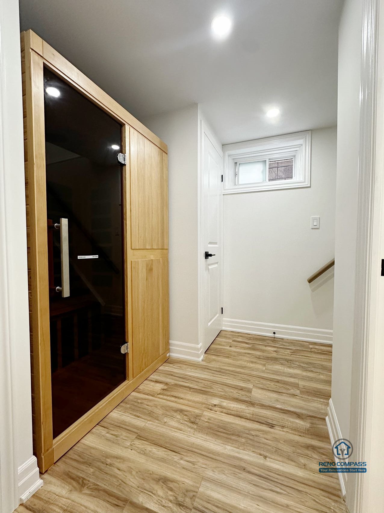 This Pickering basement renovation features a custom-built sauna integrated into a clean and functional circulation space. Completed by a Toronto renovation company, the project combines durable wood finishes, modern lighting, and wood-look flooring to create a wellness-focused area that enhances daily comfort while maintaining a seamless connection to the rest of the basement layout.