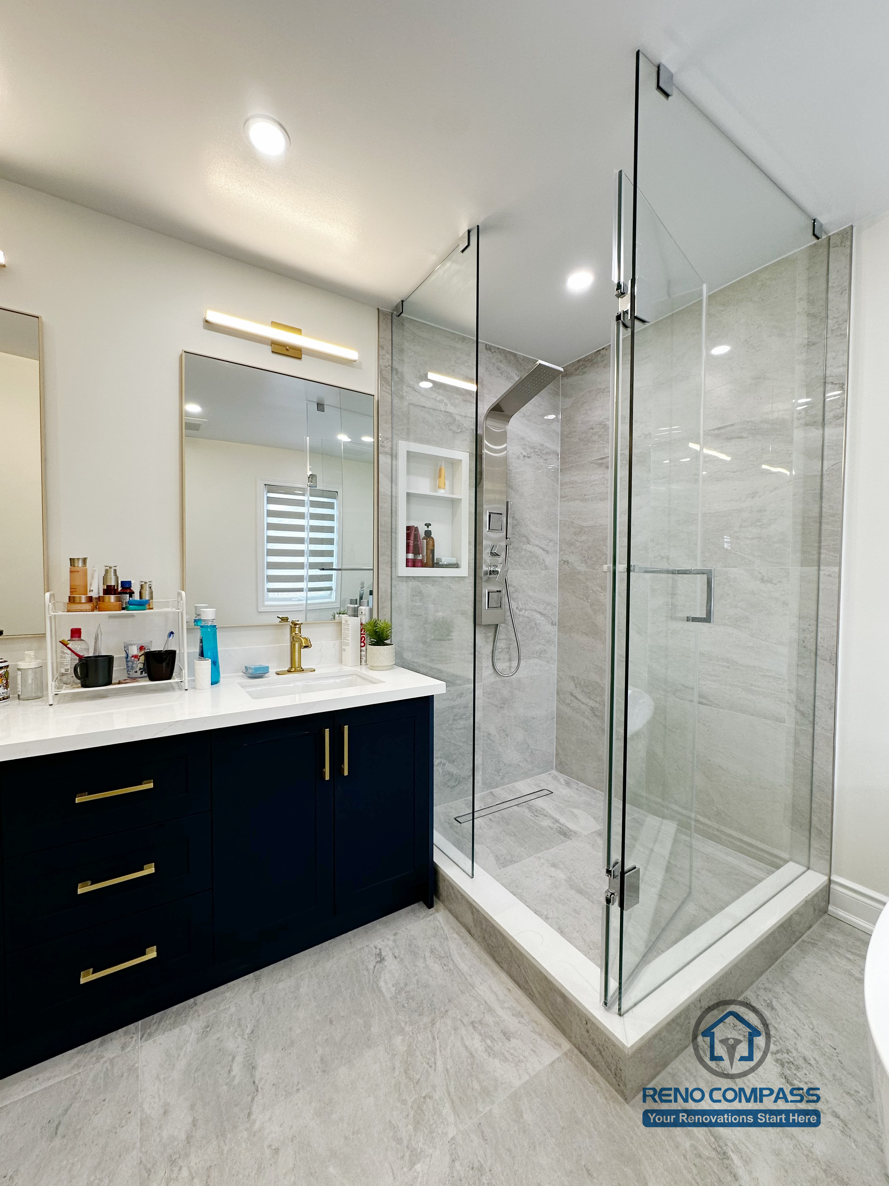 Master bathroom renovation in Markham featuring a frameless glass shower, large-format tile finishes, a custom vanity with matte black cabinetry, and brass fixtures. The design combines clean lines, efficient layout, and a refined modern aesthetic for everyday comfort.