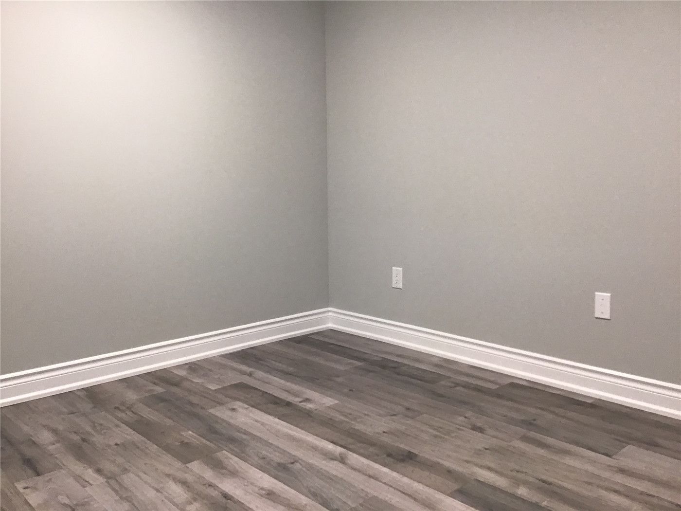 Spacious open-concept basement renovation in Newmarket featuring custom built-in shelving, a modern TV feature wall with marble-style backdrop, and sleek grey vinyl flooring. This functional and elegant design creates the perfect entertainment and family living space.