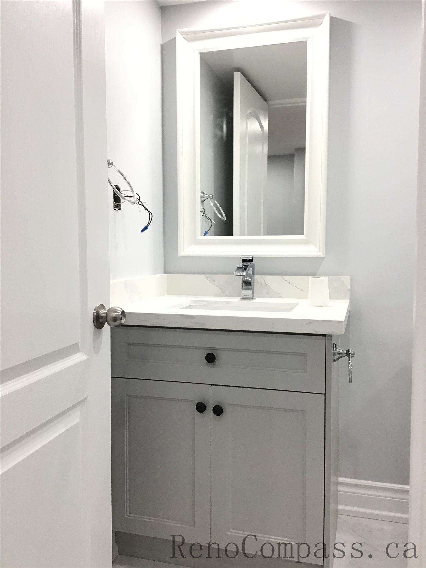 Newly renovated basement bathroom in Richmond Hill featuring a modern grey vanity cabinet, white quartz countertop, framed mirror, and sleek chrome faucet. Clean lines and neutral tones create a bright and functional space as part of a professional basement renovation project by a Toronto Renovation Company.