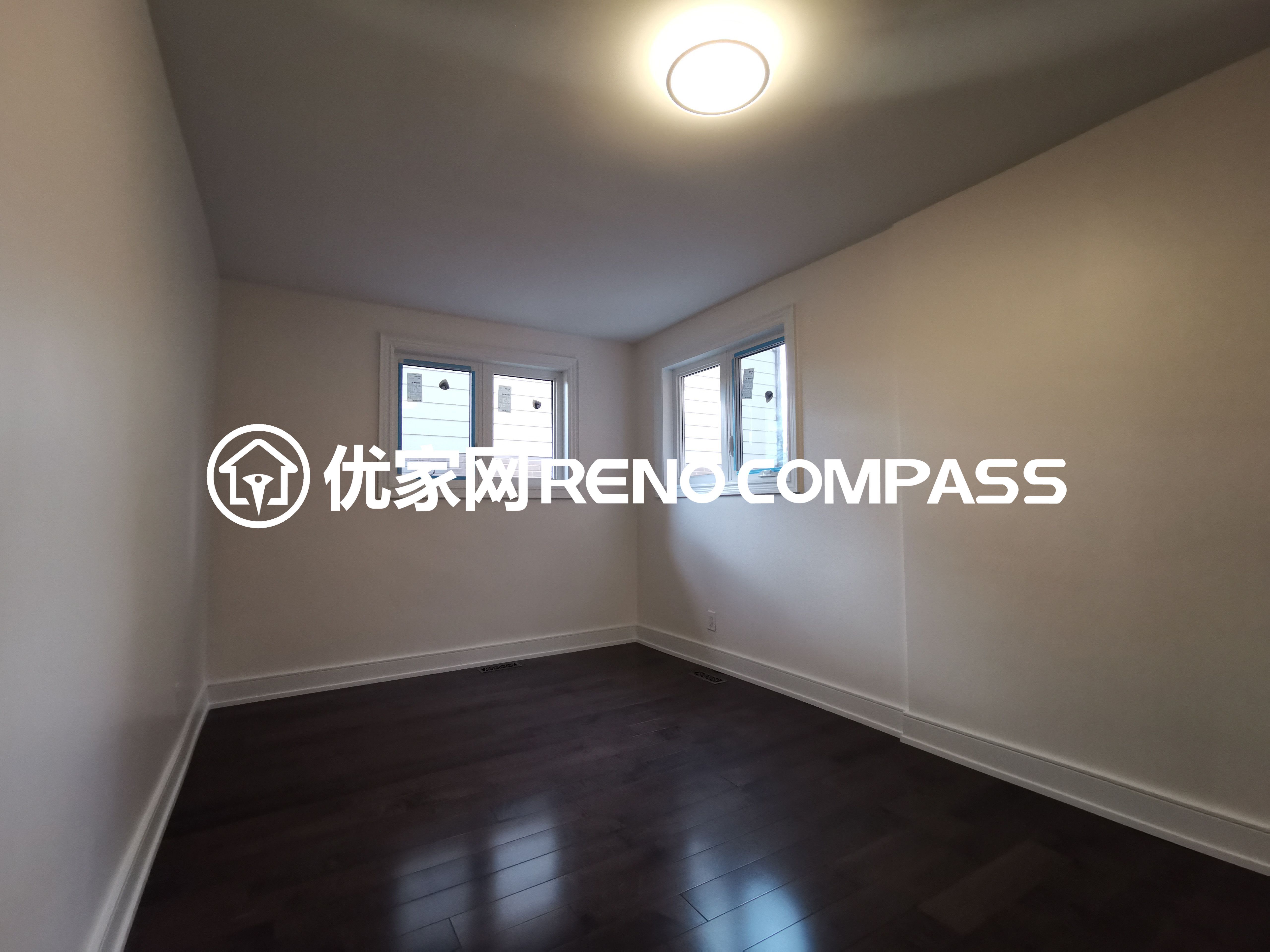 This image features a bright and freshly renovated bedroom completed as part of a North York interior renovation project. The space showcases dark hardwood flooring paired with clean white walls, creating a simple and timeless interior aesthetic. Recessed ceiling lighting provides even illumination, while multiple windows allow natural light to enhance the room’s openness. The neutral layout offers flexibility for various furniture arrangements, reflecting a well-executed interior upgrade focused on comfort, functionality, and long-term livability in modern Toronto homes.