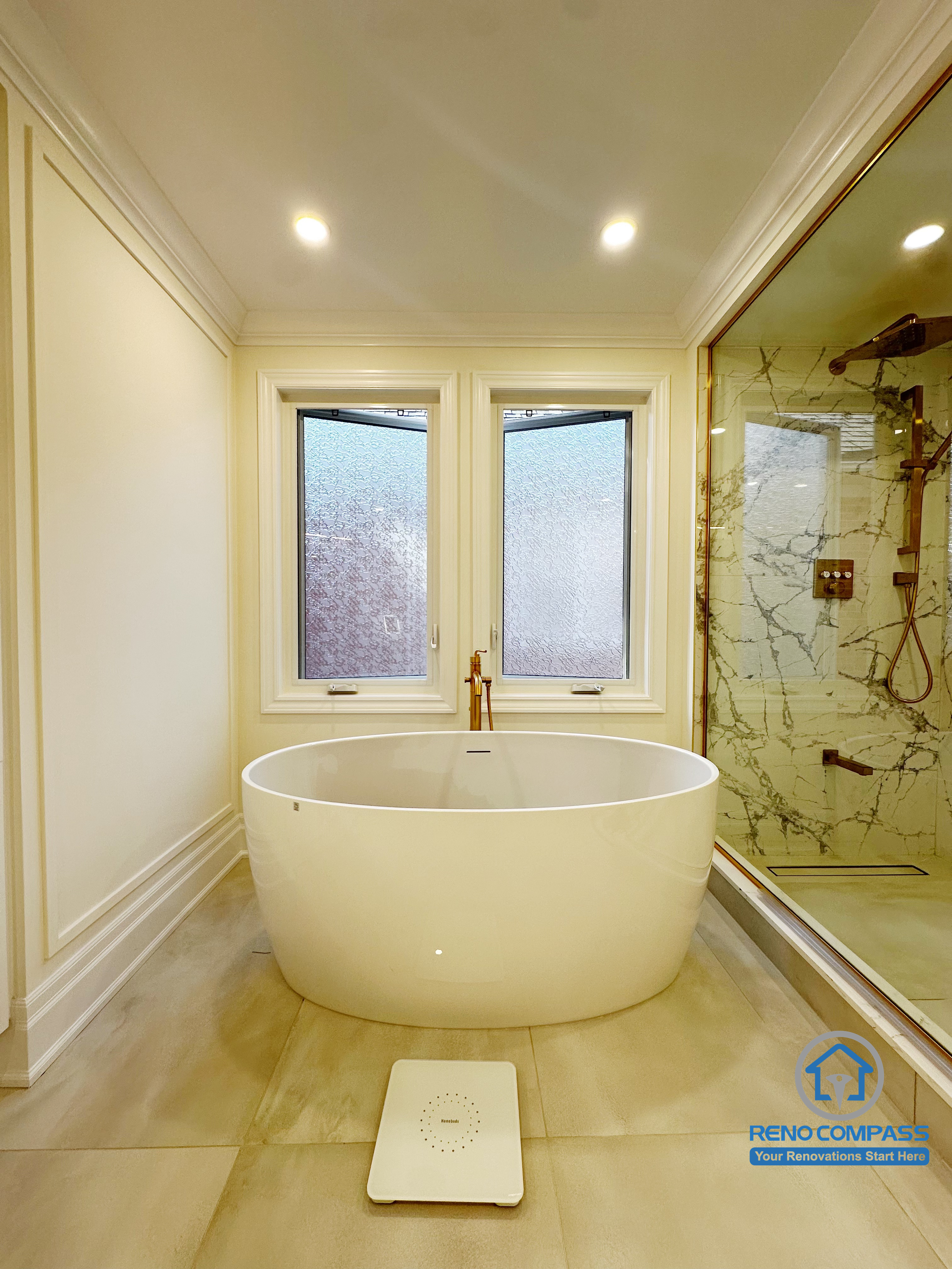 This Markham bathroom renovation features a freestanding bathtub positioned between two windows, creating a calm and symmetrical focal point. The layout emphasizes natural light, clean wall detailing, and generous circulation around the tub area. Paired with neutral tile flooring and refined trim work, the space is designed to feel open, balanced, and well-proportioned—offering a dedicated soaking zone that enhances both comfort and visual clarity.