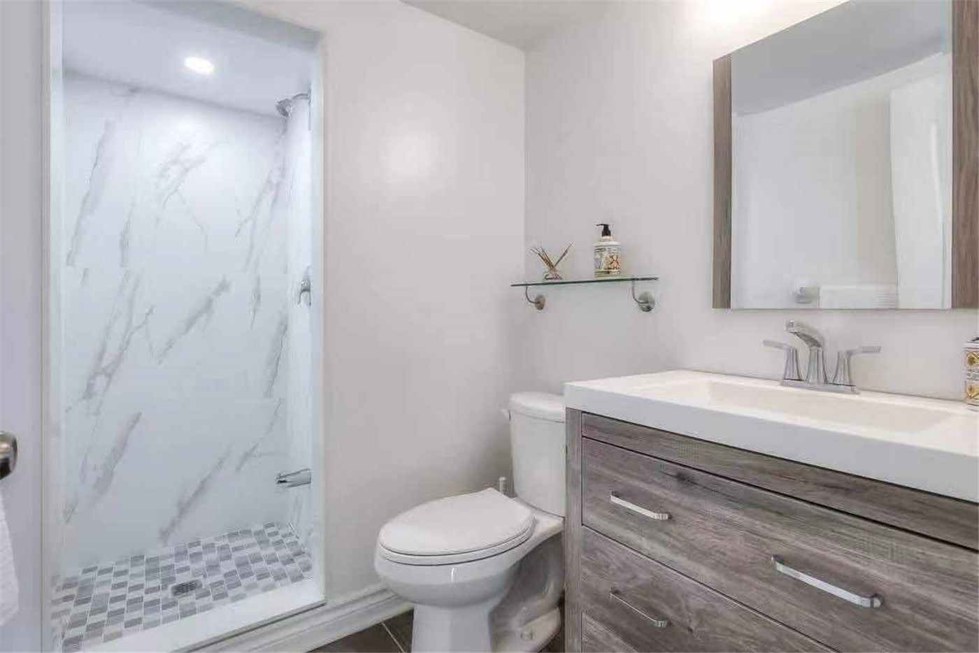 This Thornhill bathroom renovation features a modern walk-in shower with marble-style wall tiles and mosaic shower floor, paired with a contemporary vanity and quartz countertop. The clean layout, updated fixtures, and neutral color palette create a bright and functional bathroom space. Completed by a professional Toronto renovation team, this upgrade delivers a stylish and practical bathroom design suited for modern family living.