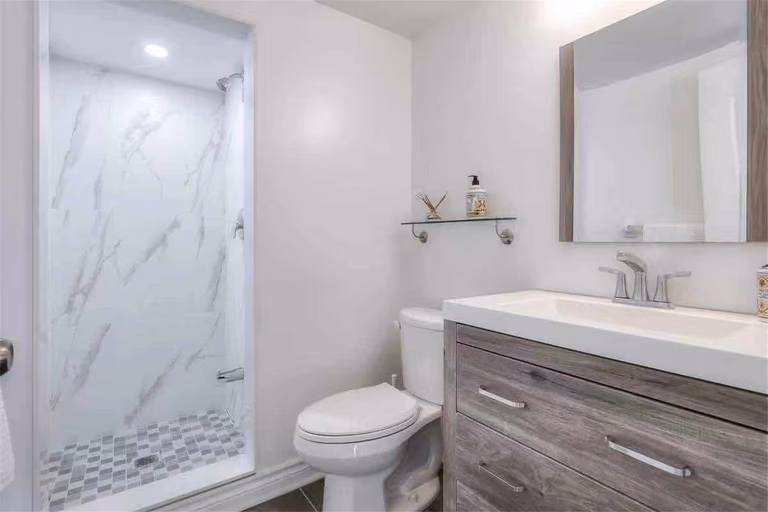 This Thornhill bathroom renovation features a modern walk-in shower with marble-style wall tiles and mosaic shower floor, paired with a contemporary vanity and quartz countertop. The clean layout, updated fixtures, and neutral color palette create a bright and functional bathroom space. Completed by a professional Toronto renovation team, this upgrade delivers a stylish and practical bathroom design suited for modern family living.