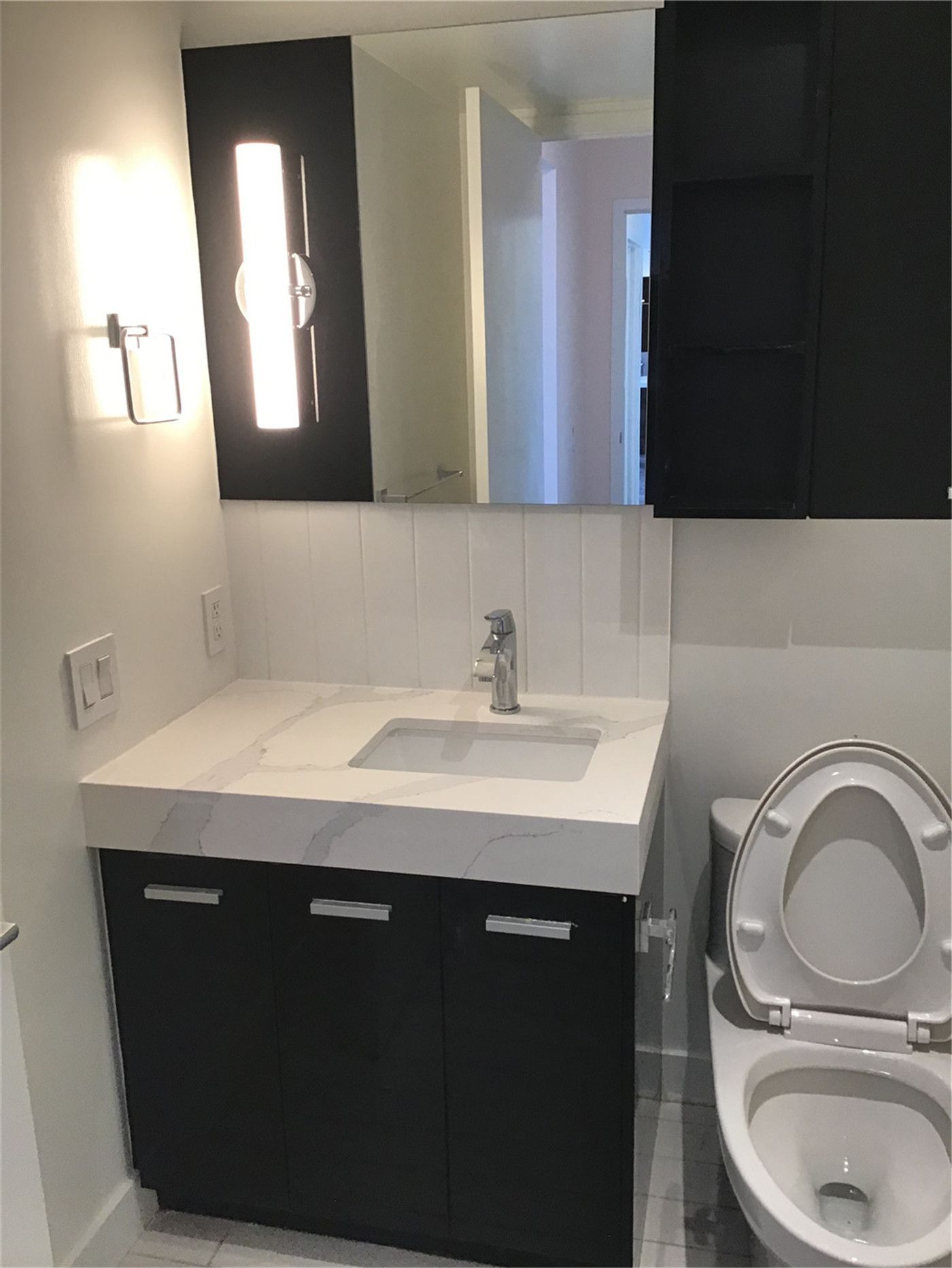 Modern condo bathroom renovation in North York featuring a sleek vanity cabinet, integrated sink, contemporary mirror lighting, and clean white tile finishes. This professional interior upgrade enhances functionality, storage, and overall aesthetics. Completed by a trusted Toronto renovation company, Reno Compass Inc., specializing in condo and residential renovation projects.