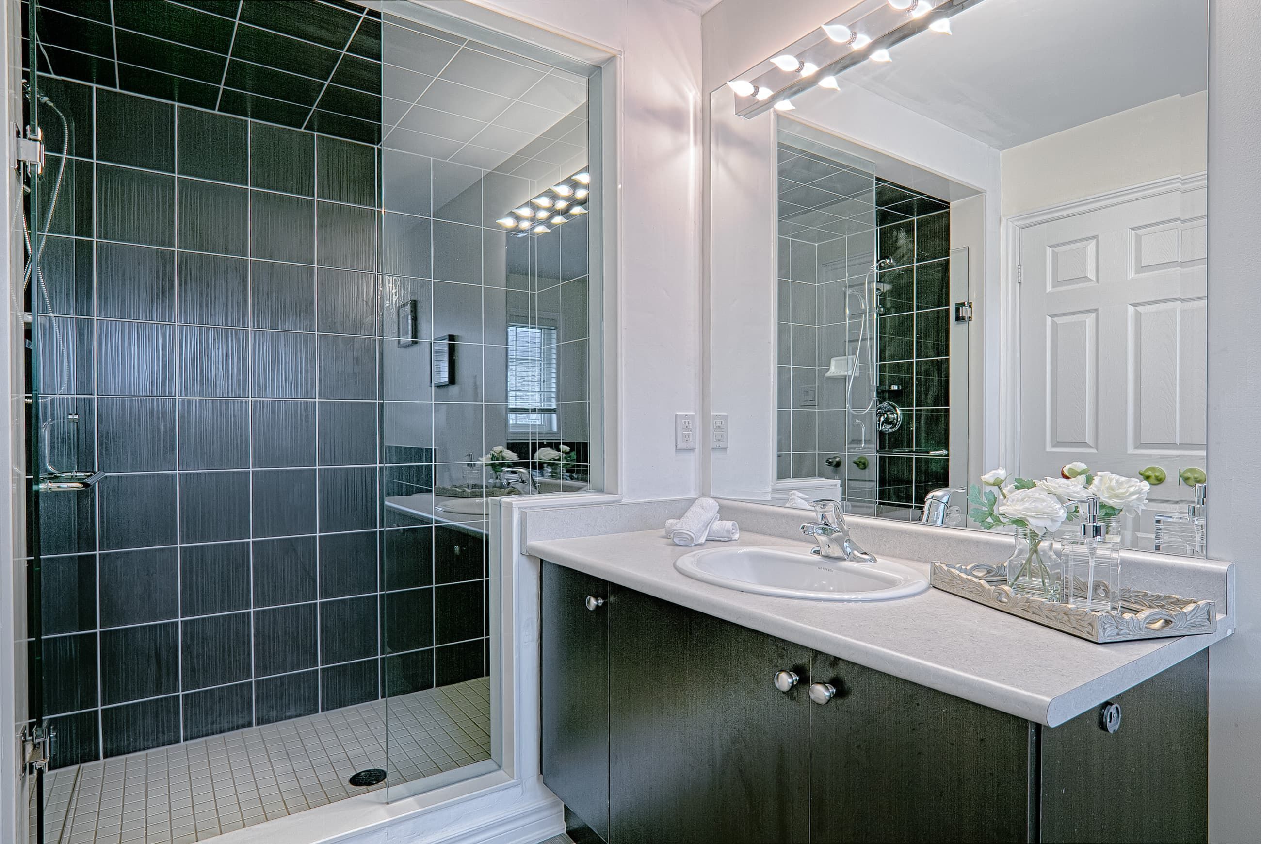 This contemporary bathroom renovation features a sleek glass-enclosed shower, modern vanity with ample storage, and a large mirror with bright overhead lighting to enhance the sense of space. Neutral wall tones and durable floor tiles create a clean and timeless design suitable for everyday living. Designed with both comfort and functionality in mind, this bathroom upgrade reflects the quality workmanship of a trusted Toronto renovation company specializing in complete residential interior renovation and modern home improvements.