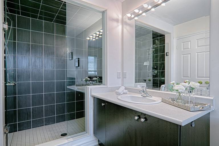This contemporary bathroom renovation features a sleek glass-enclosed shower, modern vanity with ample storage, and a large mirror with bright overhead lighting to enhance the sense of space. Neutral wall tones and durable floor tiles create a clean and timeless design suitable for everyday living. Designed with both comfort and functionality in mind, this bathroom upgrade reflects the quality workmanship of a trusted Toronto renovation company specializing in complete residential interior renovation and modern home improvements.