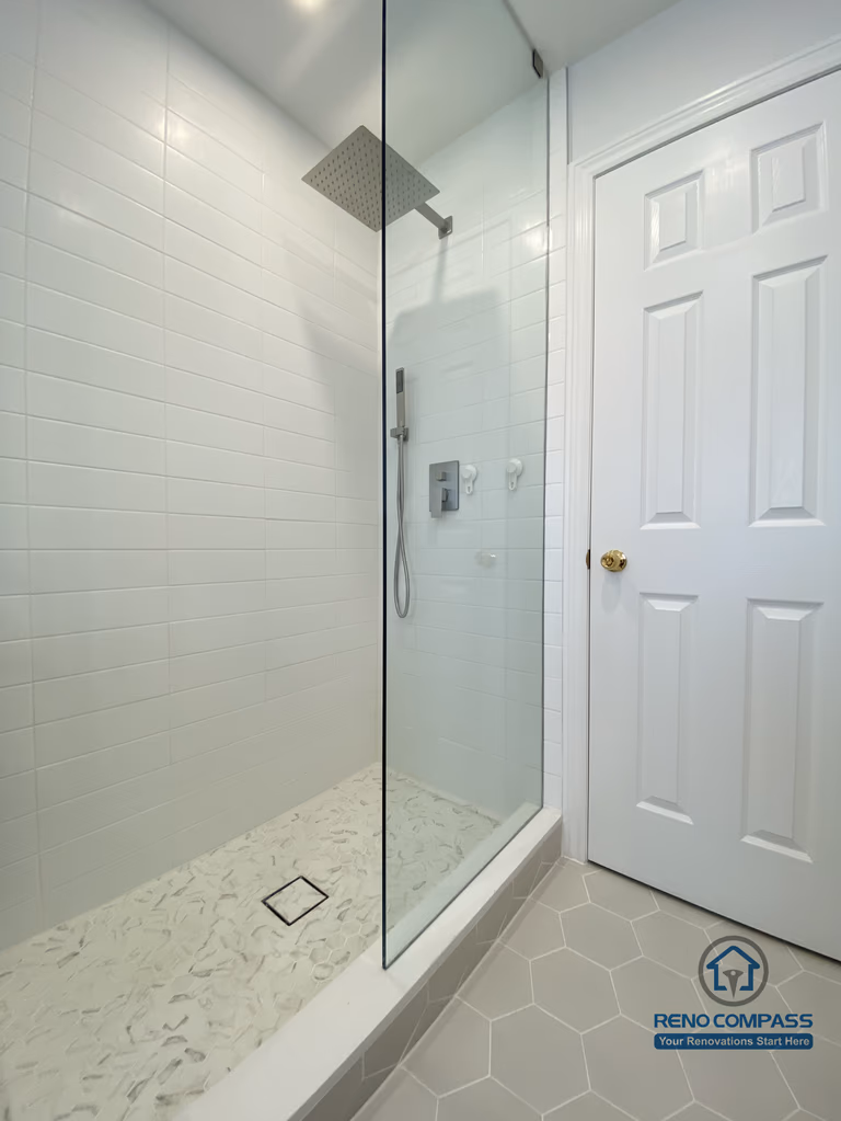 This Markham bathroom renovation features a frameless glass shower enclosure with a rainfall shower head, white subway wall tiles, and a custom tiled shower base. The clean lines and moisture-resistant materials create a modern, easy-to-maintain shower space, completed by an experienced Toronto renovation company.
