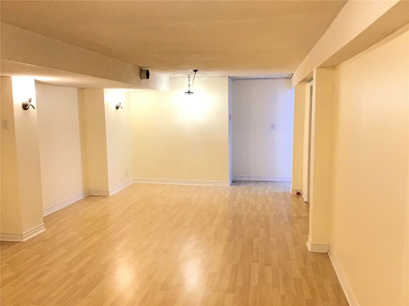This Whitby basement renovation showcases a spacious finished living area featuring warm-tone laminate wood flooring and a clean, open layout. The neutral walls and integrated lighting create a comfortable and inviting atmosphere, making the space ideal for a family room, recreation area, or multi-purpose basement setup. The updated flooring enhances durability while adding warmth to the lower level.