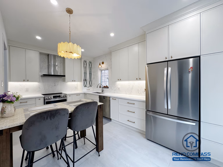 This Markham kitchen renovation features a bright open-concept layout with full-height custom cabinetry, a functional central island, and integrated seating. Clean white finishes are paired with quartz countertops and stainless steel appliances to create a timeless and highly functional cooking space. Carefully planned lighting and streamlined storage enhance both daily usability and overall visual balance, resulting in a kitchen designed for long-term living and seamless entertaining.