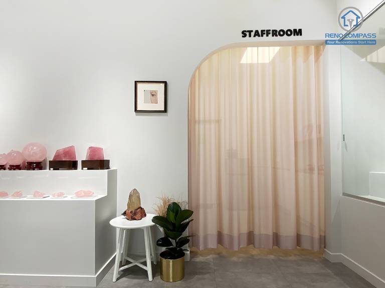 This image showcases a thoughtfully designed staff room entrance within a crystal shop renovation in Markham. A custom curved archway combined with soft sheer curtains creates a gentle transition between public retail space and private staff area. The surrounding crystal displays, minimalist finishes, and polished concrete flooring maintain visual consistency throughout the store. As a Toronto renovation company, Reno Compass designs retail spaces that balance customer-facing aesthetics with functional back-of-house planning.