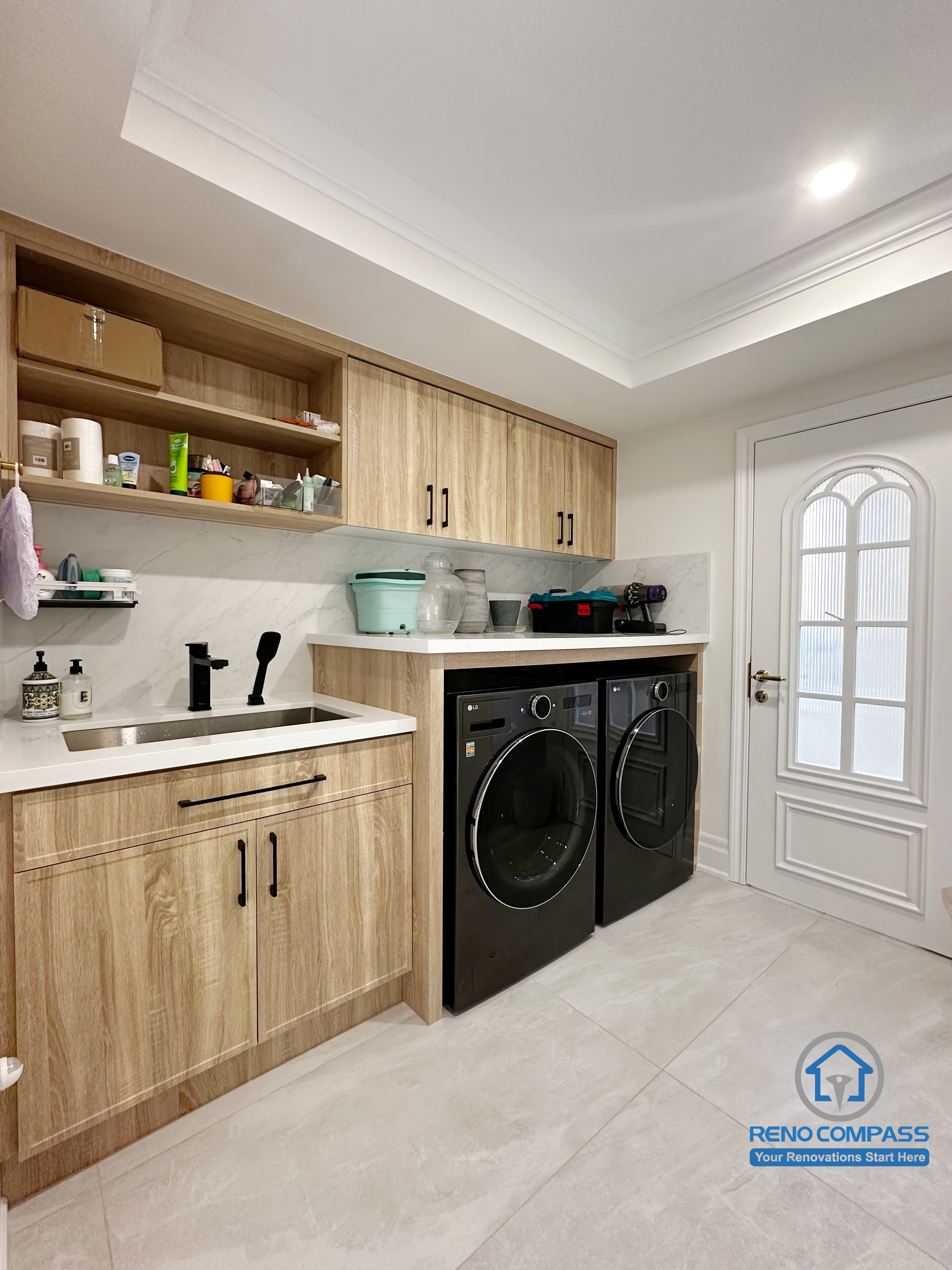 This custom laundry room was completed as part of a full interior renovation in Markham. The space was designed with practicality and durability in mind, featuring wood-grain cabinetry for concealed storage, open shelving for daily essentials, and an integrated countertop with utility sink. Front-loading washer and dryer units were built seamlessly into the layout to maintain a clean, organized appearance, while the neutral finishes and recessed lighting help keep the room bright and easy to maintain for everyday household use.