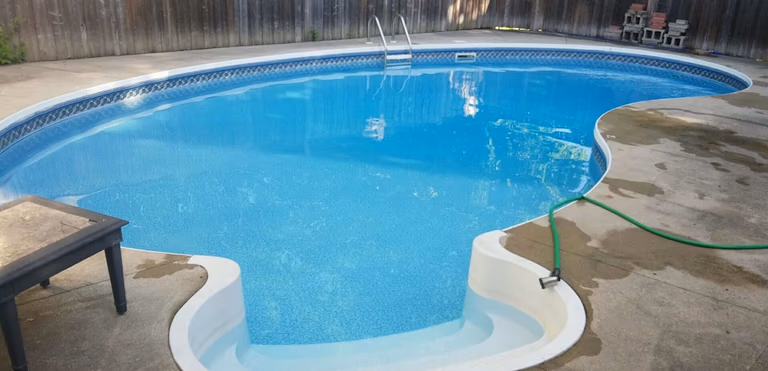After renovation photo of a fully restored backyard swimming pool in Toronto. The new bright blue liner, clean water, and resurfaced edges highlight the professional pool transformation from old and damaged to modern and inviting. Expert pool renovation by local Toronto specialists.