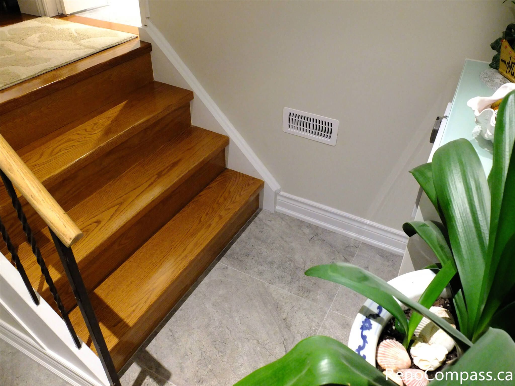 A high-quality interior renovation in North York featuring polished oak hardwood stairs paired with large-format grey porcelain floor tiles. The transition showcases expert craftsmanship in baseboard installation and flooring integration, creating a clean, modern entryway for a residential home.