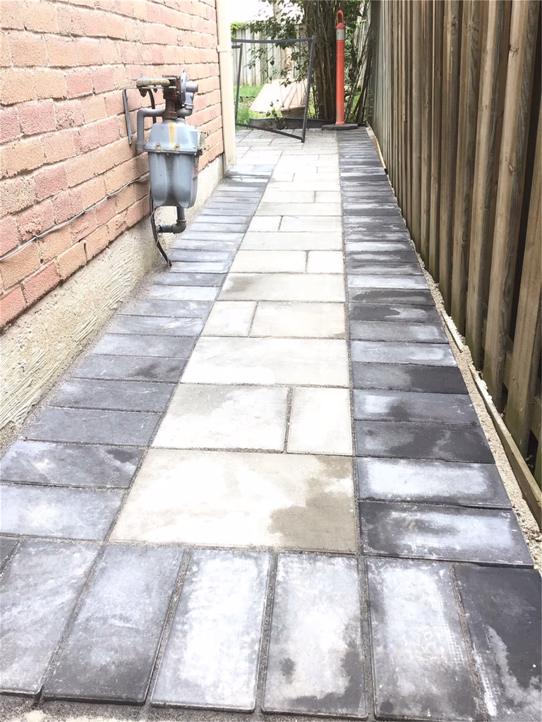 This Oakville interlocking project showcases a clean and functional side walkway built with durable grey pavers and a contrasting dark border design. Installed along the side of the home, the pathway improves drainage, accessibility, and overall property maintenance. The precise layout and professional finish create a sleek, low-maintenance solution ideal for narrow side yard spaces.