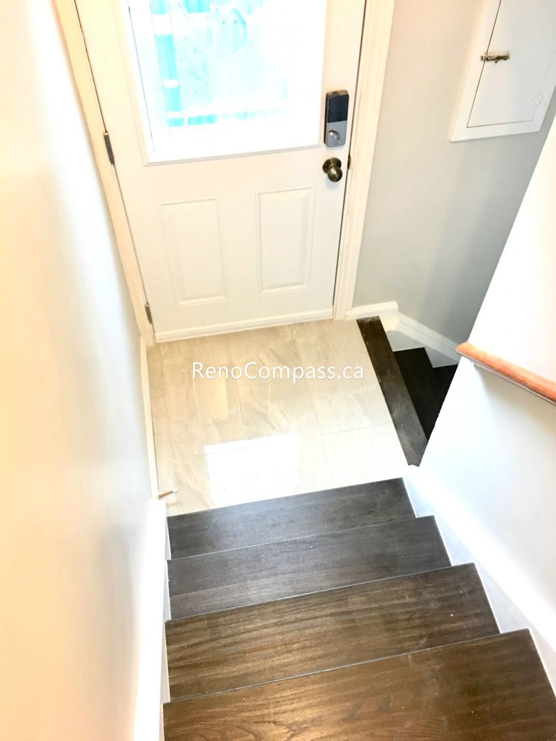 This Toronto basement renovation features an upgraded staircase and entryway with modern dark wood steps and durable tile flooring near the entrance. The clean finishes and improved layout create a safe, stylish, and functional transition between levels. Completed by Reno Compass Inc., this renovation enhances both visual appeal and everyday durability, delivering a polished and cohesive basement living environment.