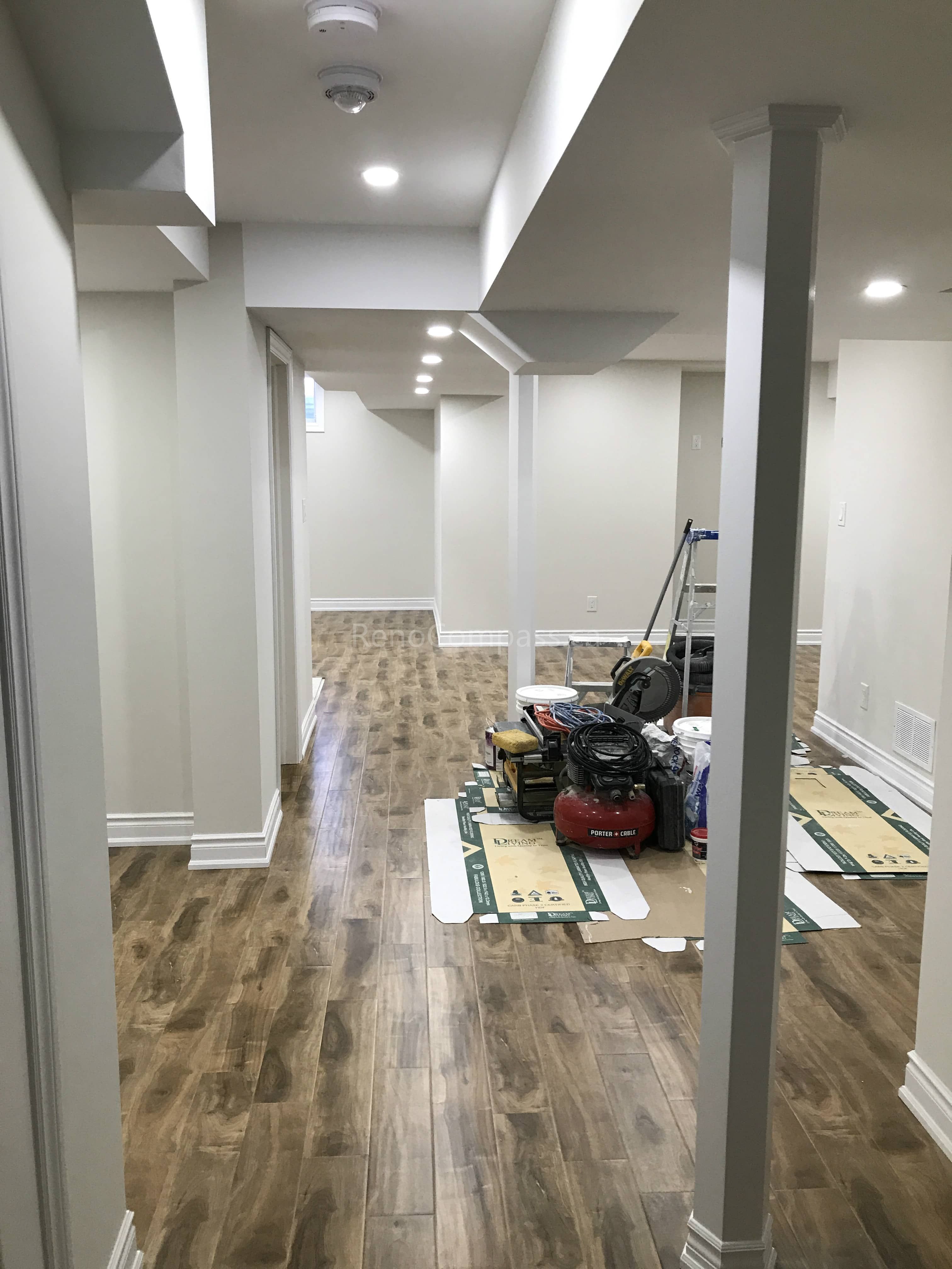 This Toronto basement renovation showcases a newly finished hallway with modern flooring, recessed pot lights, and clean wall and ceiling detailing. The upgraded layout improves flow and functionality while creating a bright and welcoming lower-level living space. Completed by Reno Compass, a professional Toronto renovation company, this project highlights quality craftsmanship and practical basement design for modern homes.