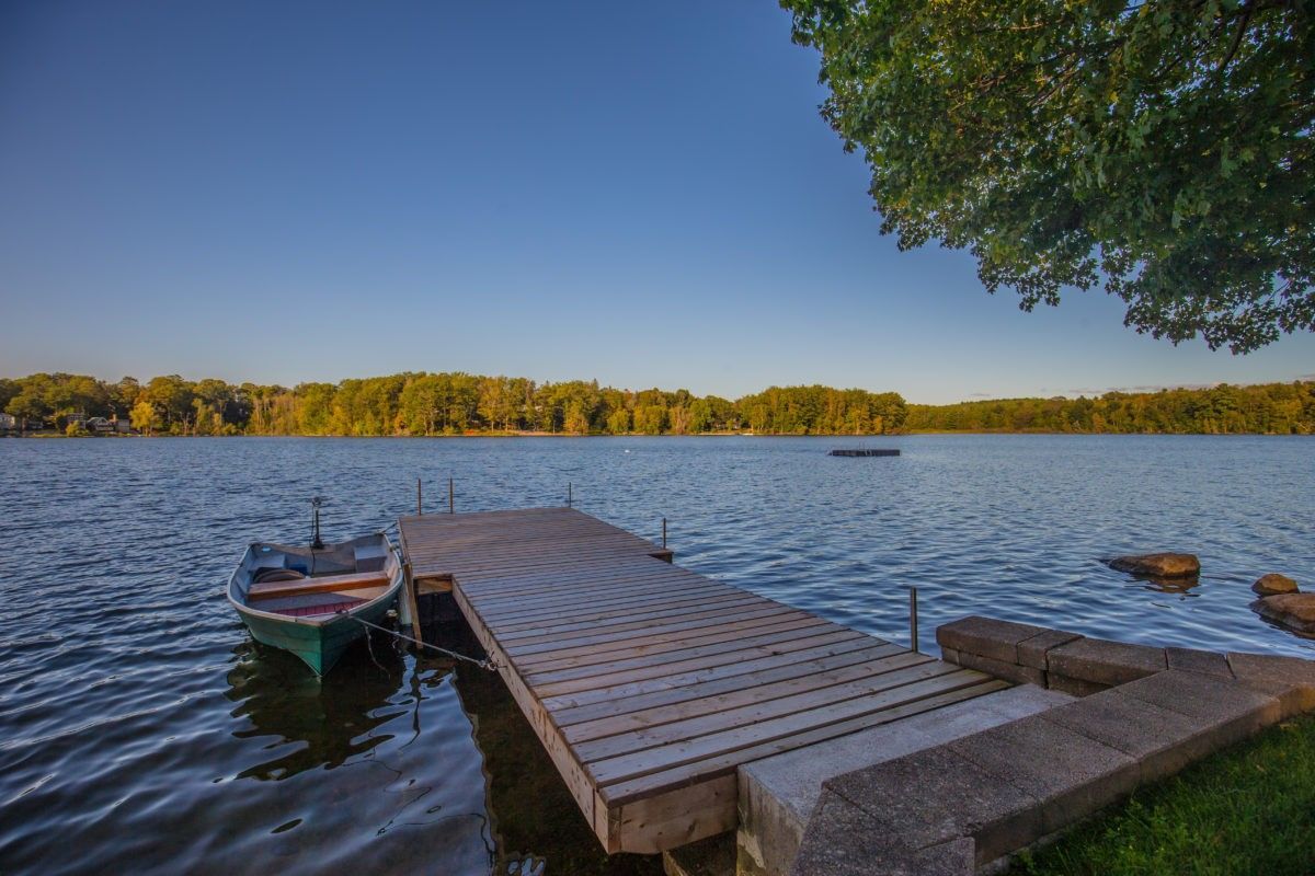 Scenic backyard waterfront view of a luxury Toronto home renovation featuring a private wooden dock, tranquil lake setting, and landscaped shoreline. This exterior lifestyle space highlights seamless indoor-outdoor living with direct water access, natural surroundings, and premium residential property enhancement. Part of a 5000 sqft custom home renovation project completed by Reno Compass Inc., a professional Toronto renovation company specializing in high-end residential transformations and full-property upgrades.