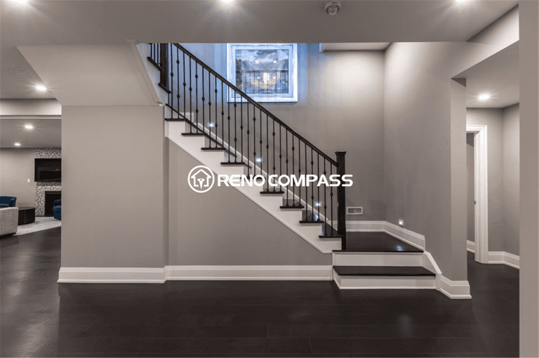 Professional basement renovation in Toronto featuring a modern staircase with iron railings, recessed lighting, and dark hardwood flooring. This well-designed basement layout improves accessibility and creates a bright, open living space, completed by a trusted Toronto renovation company, Reno Compass Inc.