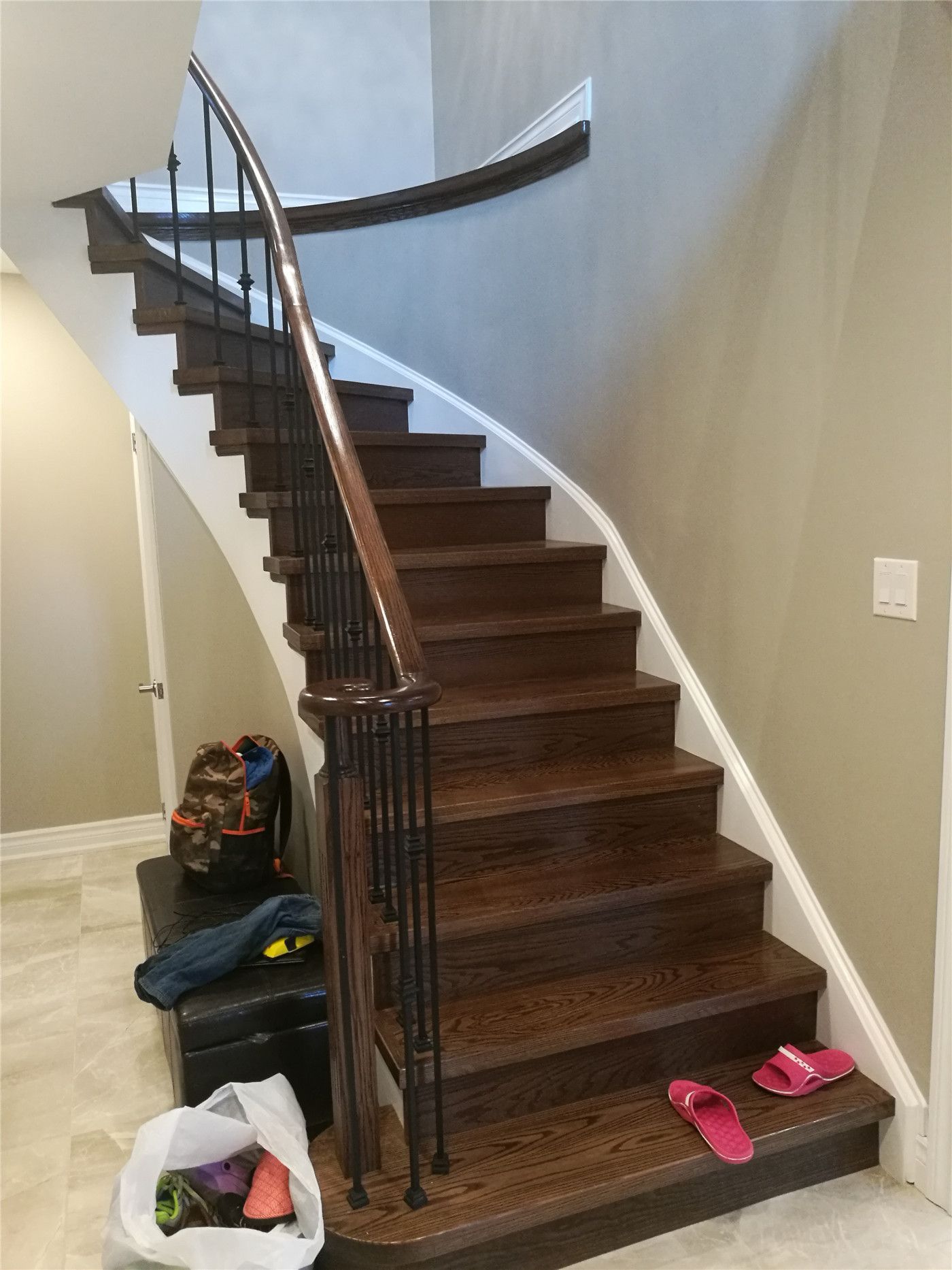 This Newmarket interior renovation highlights a curved hardwood staircase featuring dark wood treads and custom railing details. The smooth stair geometry, clean wall finishes, and precise installation demonstrate high-quality craftsmanship and structural detailing by a professional Toronto renovation company.