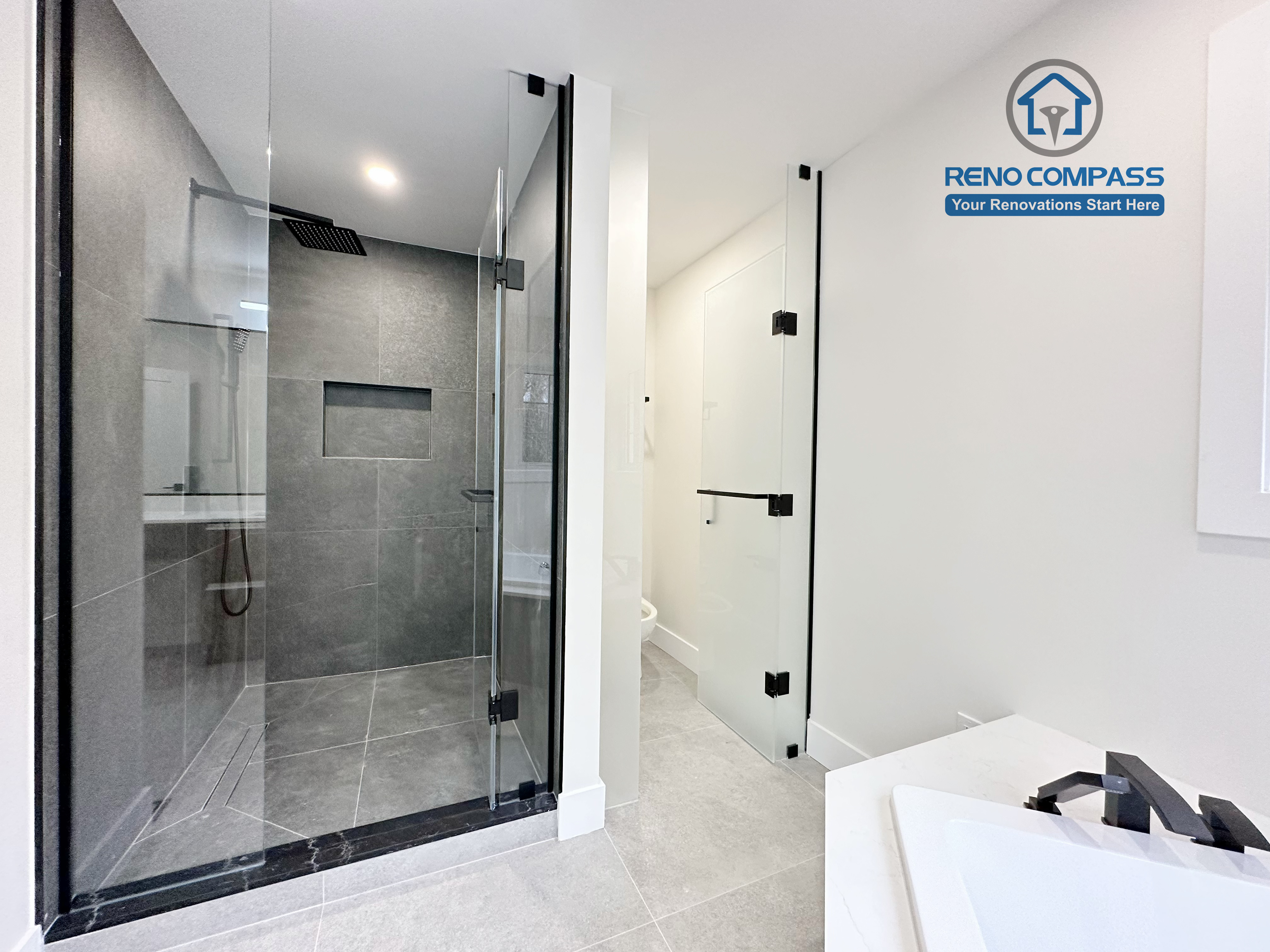 Modern bathroom renovation in Richmond Hill featuring a black-framed glass shower enclosure, large-format grey tile walls and flooring, and a clean, minimalist design that enhances both functionality and visual space.