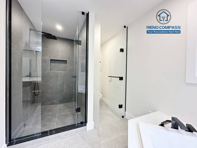 Modern bathroom renovation in Richmond Hill featuring a black-framed glass shower enclosure, large-format grey tile walls and flooring, and a clean, minimalist design that enhances both functionality and visual space.