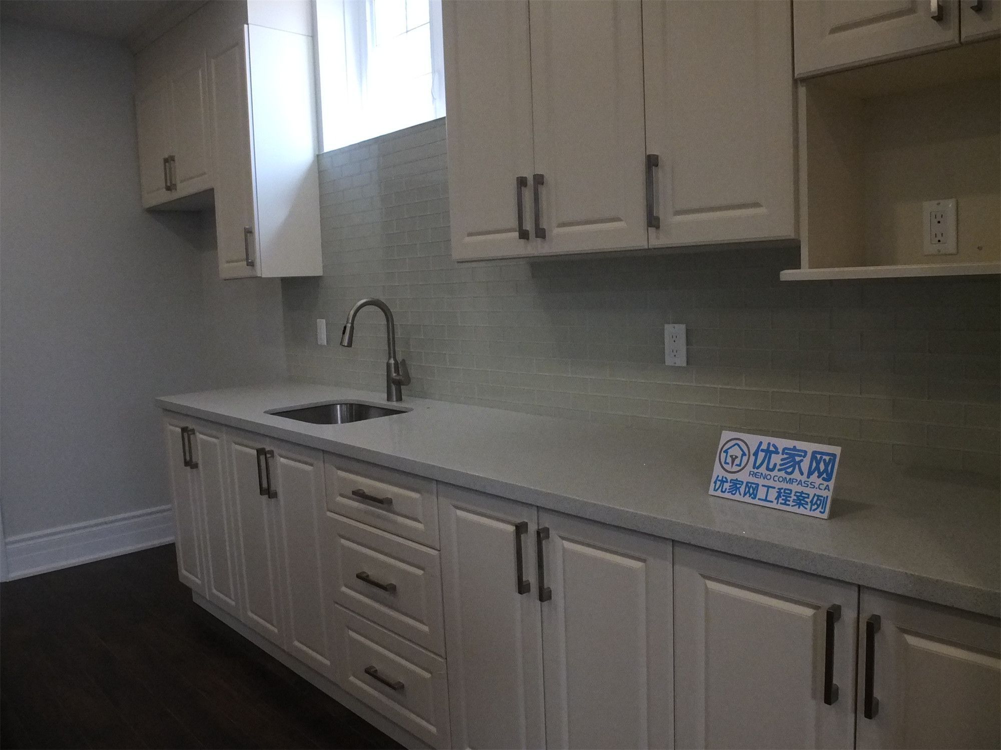 This Richmond Hill basement renovation includes a functional kitchen area featuring custom cabinetry, a built-in sink, and a clean tile backsplash. The light-colored cabinets combined with modern hardware create a bright and practical space, ideal for a basement bar, secondary kitchen, or rental suite setup.