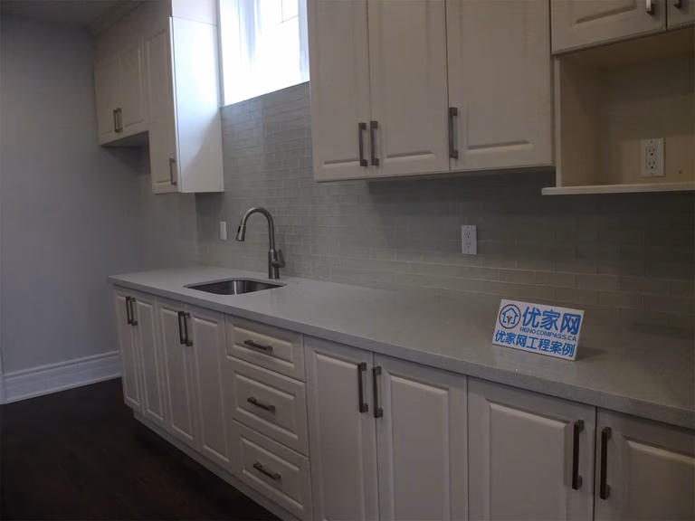 This Richmond Hill basement renovation includes a functional kitchen area featuring custom cabinetry, a built-in sink, and a clean tile backsplash. The light-colored cabinets combined with modern hardware create a bright and practical space, ideal for a basement bar, secondary kitchen, or rental suite setup.