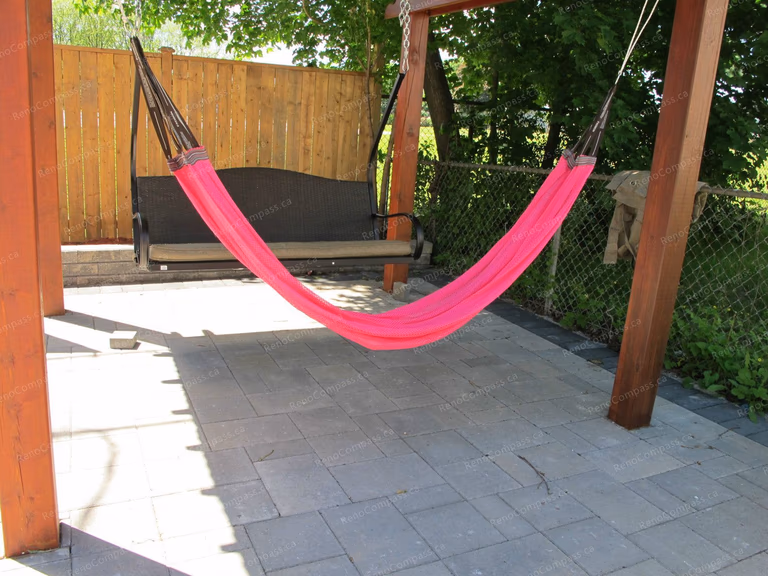 This Markham backyard landscaping project features a custom-built wooden pergola combined with a professionally installed interlock patio. The outdoor space is designed for comfort and leisure, complete with a hammock and swing seating area, creating a perfect backyard retreat. The durable stone paving enhances functionality while maintaining a clean and modern look. Completed by Reno Compass Inc., this project highlights expert craftsmanship in outdoor garden design and interlock installation, transforming the backyard into a stylish and inviting living space.