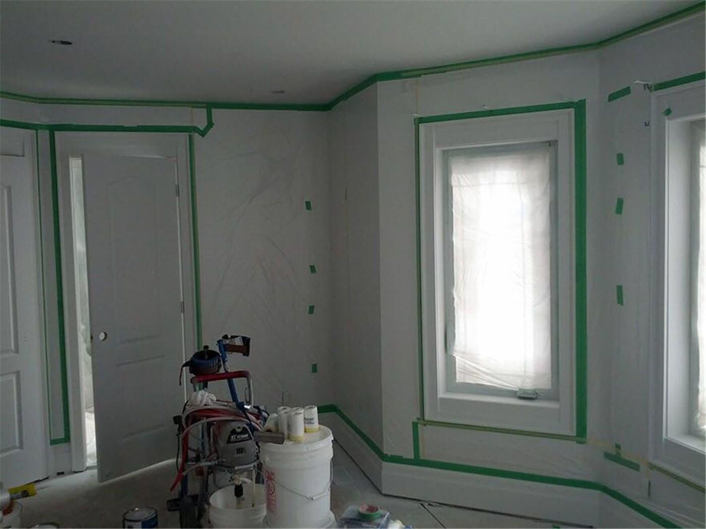This image showcases a professional interior wall painting project in Toronto, highlighting detailed surface preparation before painting. Windows, trims, and edges are carefully masked to ensure clean paint lines and a flawless finish. Our experienced Toronto painting and renovation team focuses on precision, protection, and high-quality workmanship to deliver smooth, modern interior walls for residential spaces.