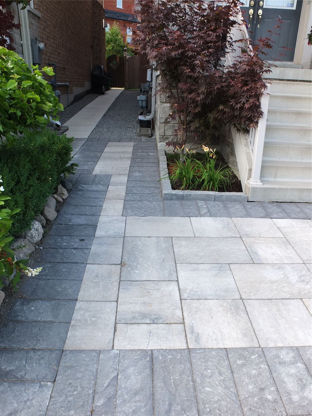 This Toronto landscaping renovation features a modern interlocking stone walkway connecting the front entrance to the backyard with clean lines and durable materials. The project includes large-format paving stones, contrasting border accents, and integrated garden beds that enhance both functionality and curb appeal. Designed for long-term durability and proper drainage, the upgraded pathway creates a safe, elegant transition between spaces while elevating the home’s exterior aesthetics. Completed by an experienced Toronto renovation and landscaping team, this project adds lasting value and a refined outdoor look.