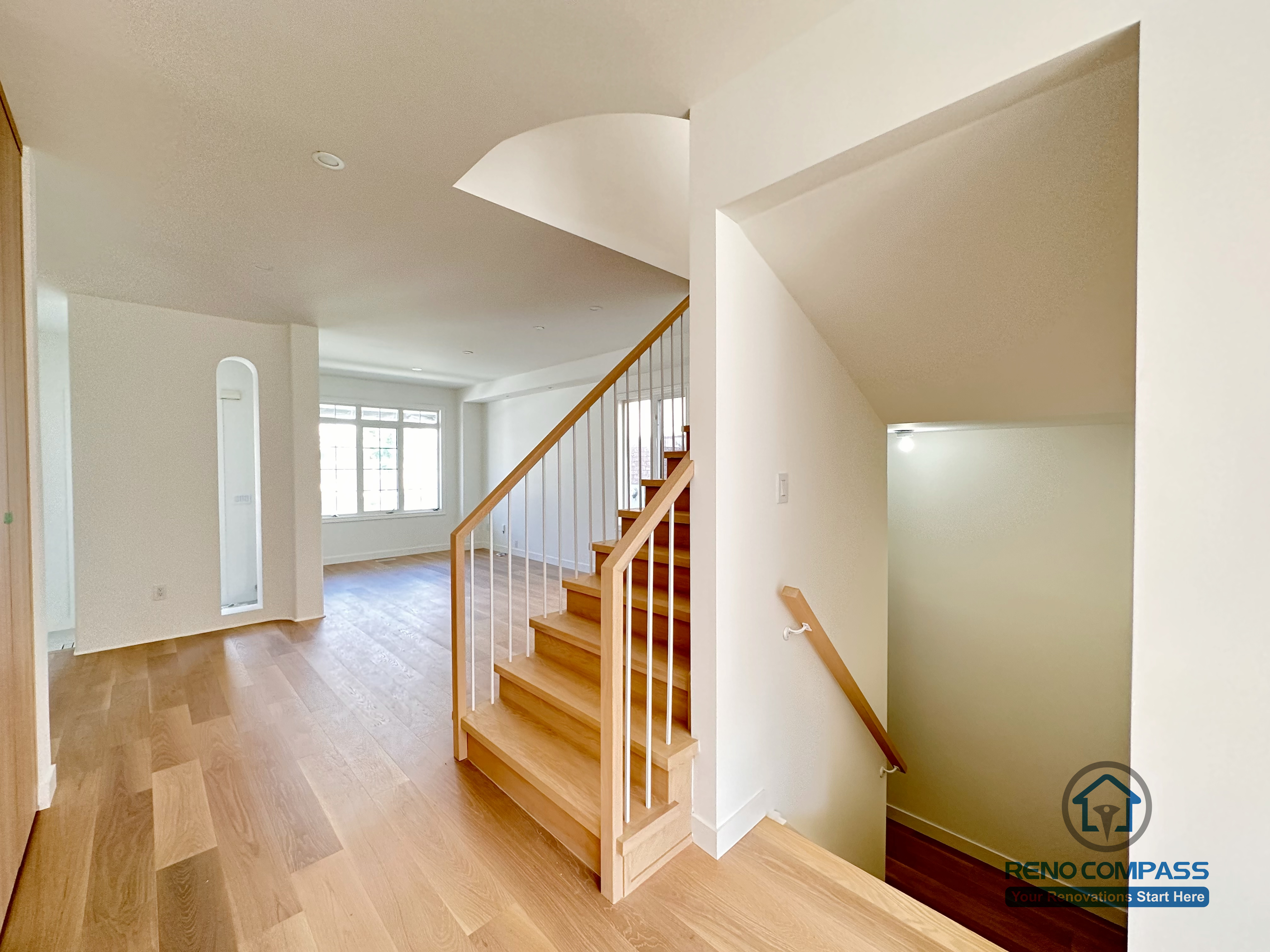 This Markham flooring and stair renovation features wide-plank hardwood flooring paired with a clean, modern staircase finished with wood treads and white railing. The open layout allows natural light to flow through the space while maintaining clear circulation between levels. Completed by a professional Toronto renovation company, Reno Compass Inc., the design emphasizes durability, visual continuity, and everyday functionality.