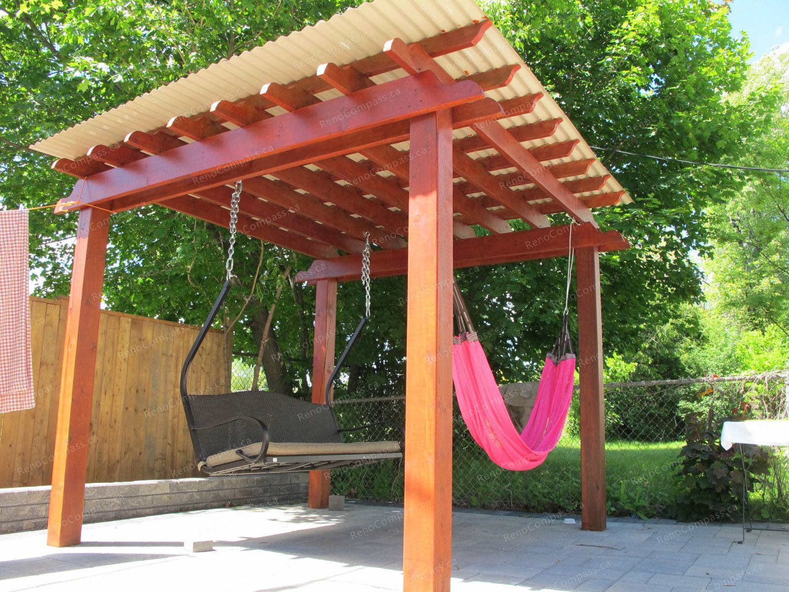 This Markham outdoor landscaping project features a custom-built wooden pergola with a covered roof, creating a stylish and functional backyard relaxation space. Designed for both comfort and durability, the structure includes a swing seating area and hammock setup, enhancing the homeowner’s outdoor living experience. Surrounded by greenery and modern patio stonework, this project showcases professional craftsmanship and thoughtful garden design by Reno Compass Inc., delivering a perfect blend of beauty and functionality for outdoor entertainment and leisure.