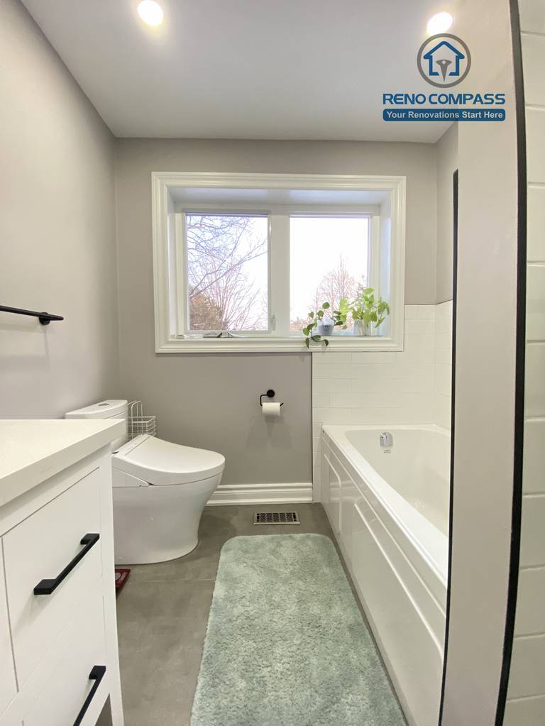 This North York bathroom renovation features a modern white vanity with a quartz countertop, matte black hardware, and a clean, functional layout. The neutral wall color, large-format floor tiles, and integrated lighting create a bright and timeless bathroom design, completed by a Toronto renovation company focused on quality craftsmanship and everyday usability.